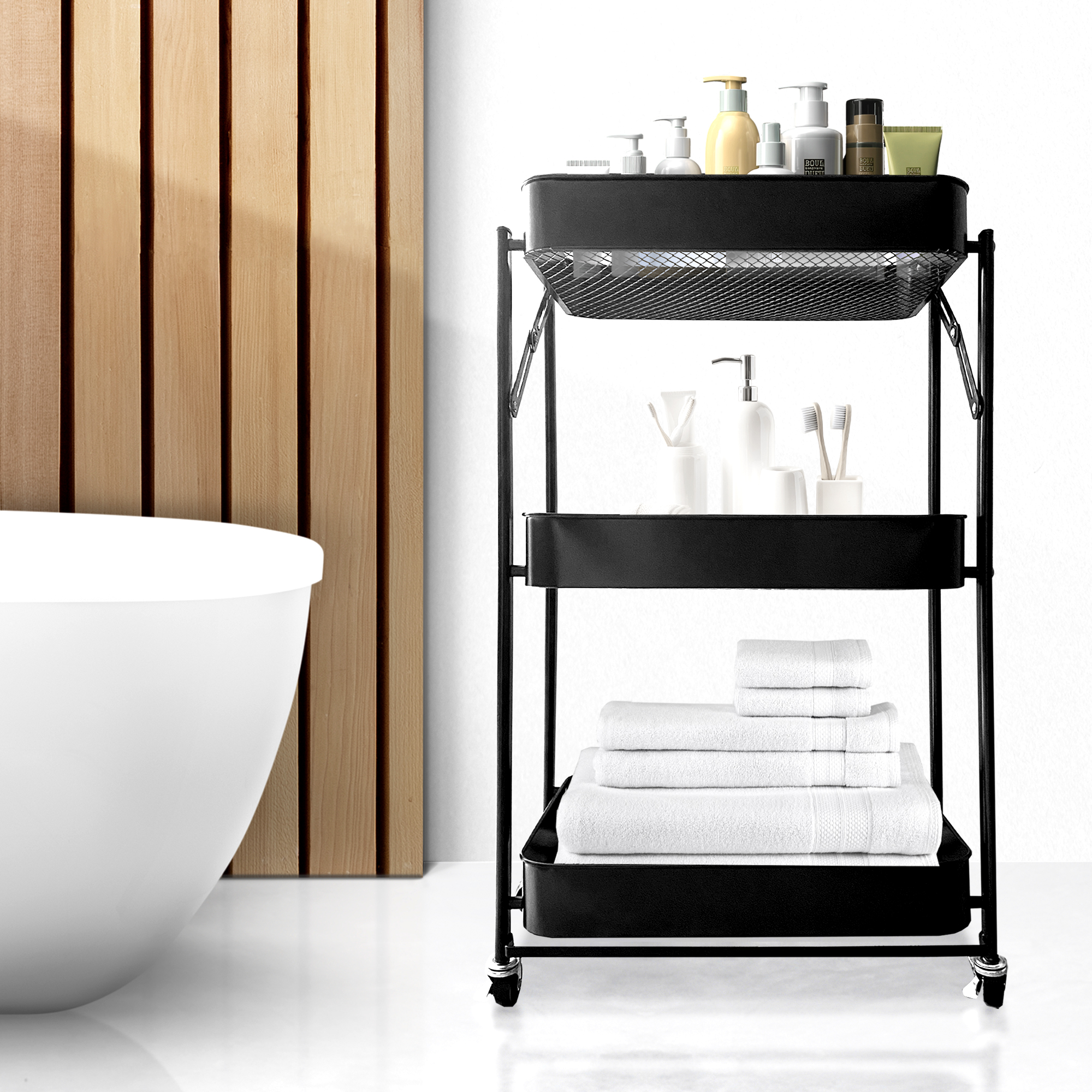 Un carrito negro de tres niveles con productos de baño y toallas.