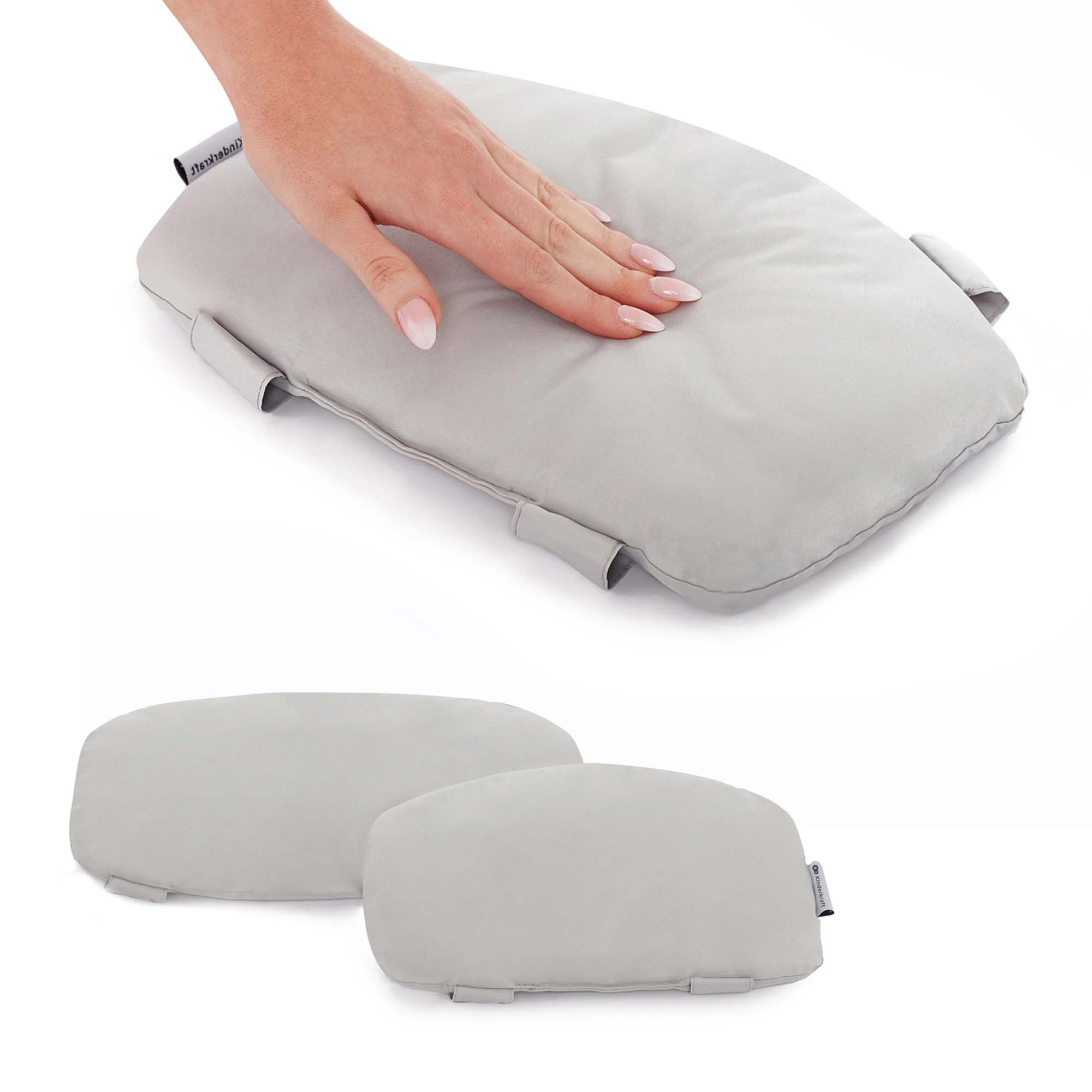 Eine Hand berührt ein graues Kissen. Zwei Kissen liegen nebeneinander.