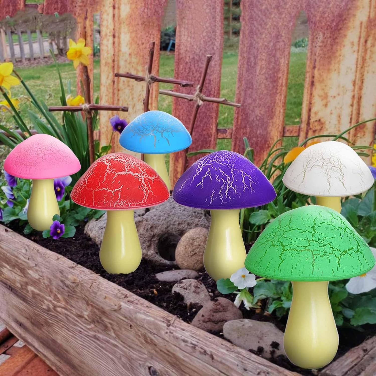 Bunte Pilzdeko im Garten mit Holz und Rostzaun.