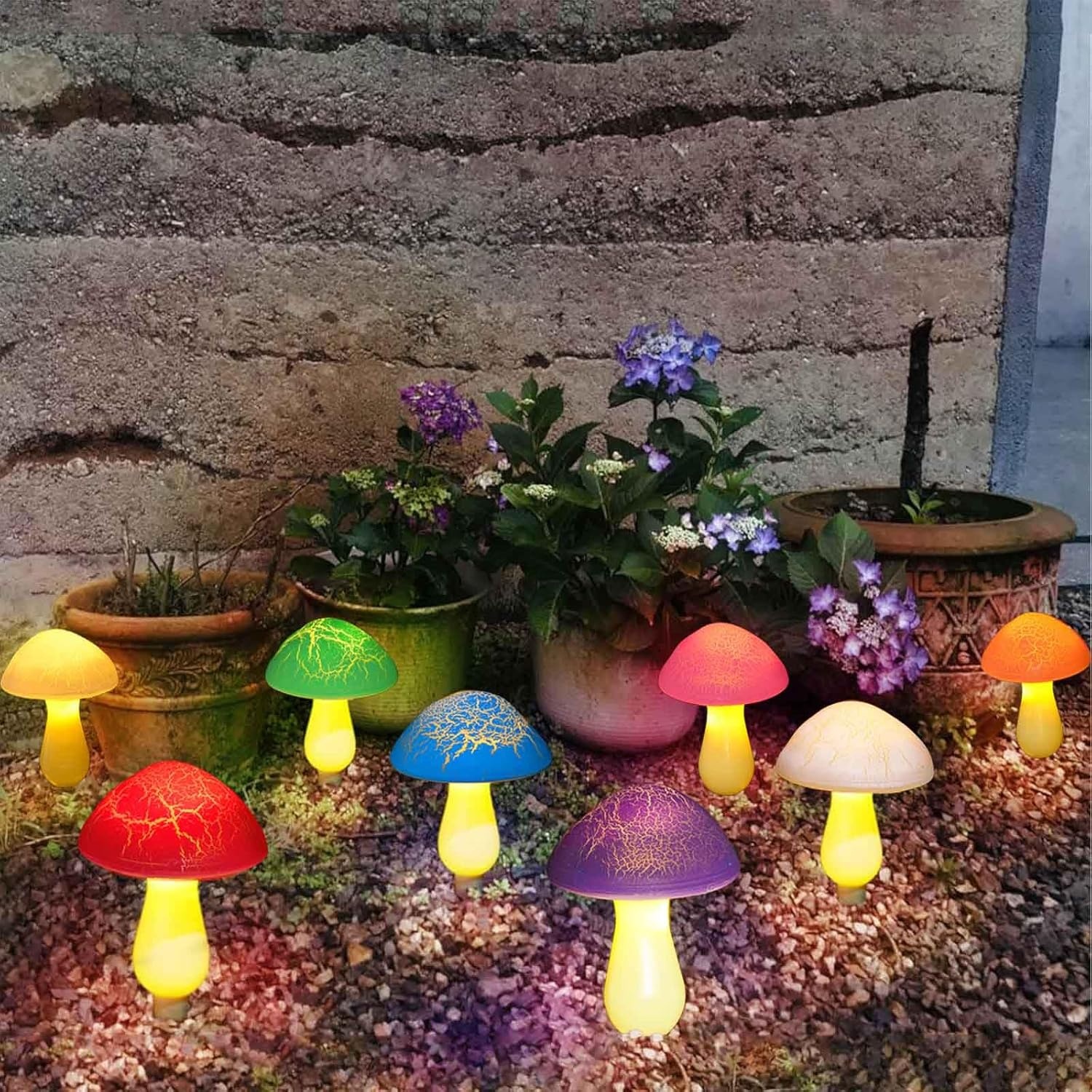 Bunte Pilz-Lichter schmücken einen Gartenweg mit Blumen und Steinmauern.