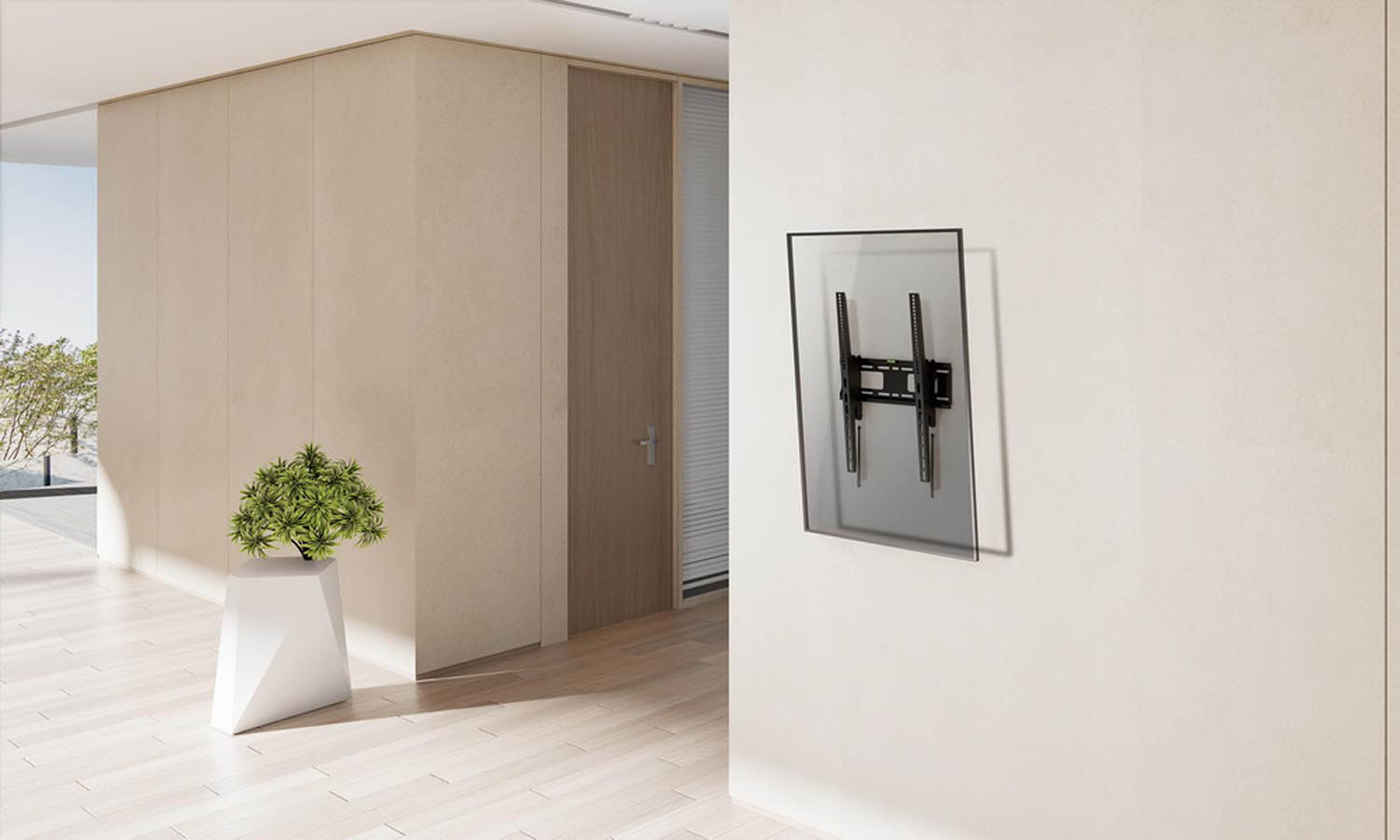 A black TV mount hangs on a white wall, next to a pot with a green plant.
