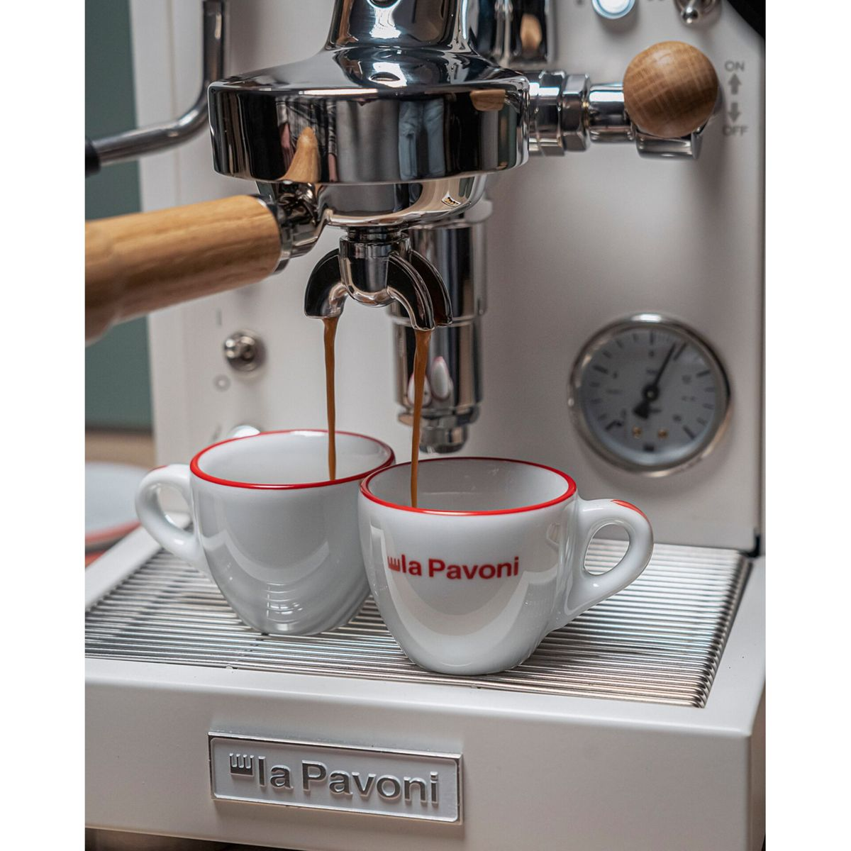 Espressomaschine brüht zwei Tassen Kaffee mit rotem Rand.