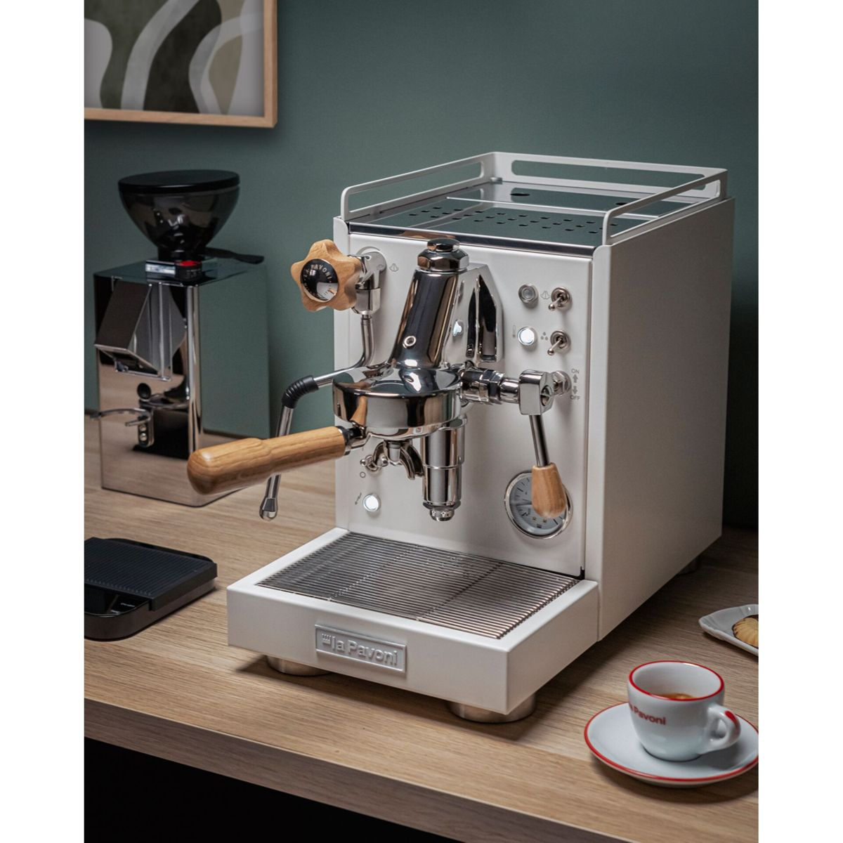 Eine weiße Espressomaschine mit Holzdetails neben einer Kaffeemühle und einer Tasse.