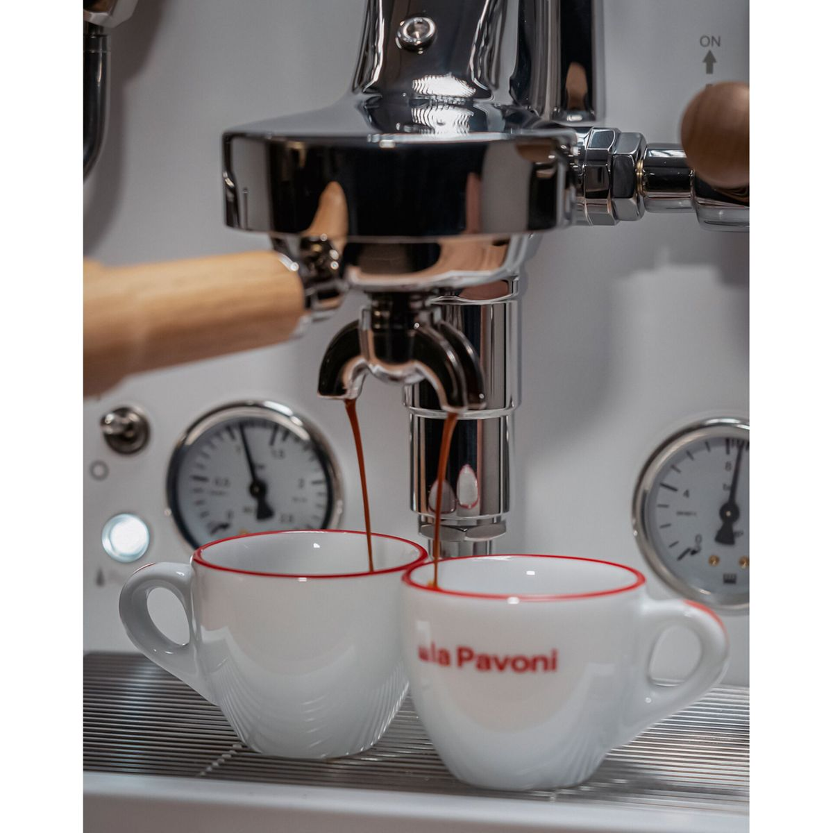 Espressostrahlen fließen in zwei weiße Tassen mit rotem Rand aus einer Espressomaschine.