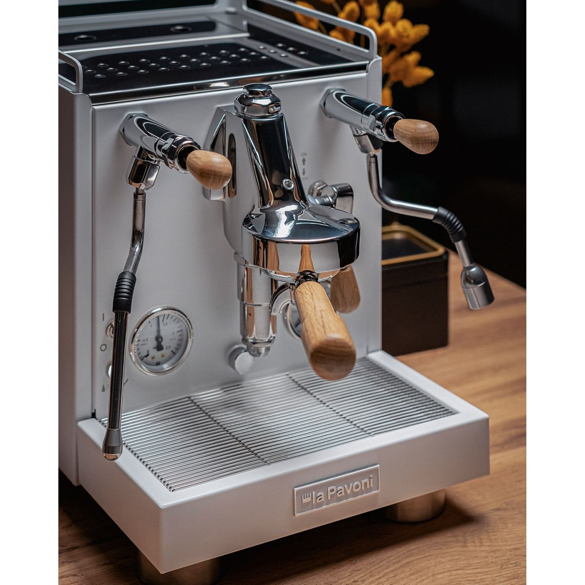 Eine silberne La Pavoni Espressomaschine mit Holzgriffen steht auf einem Holztisch.
