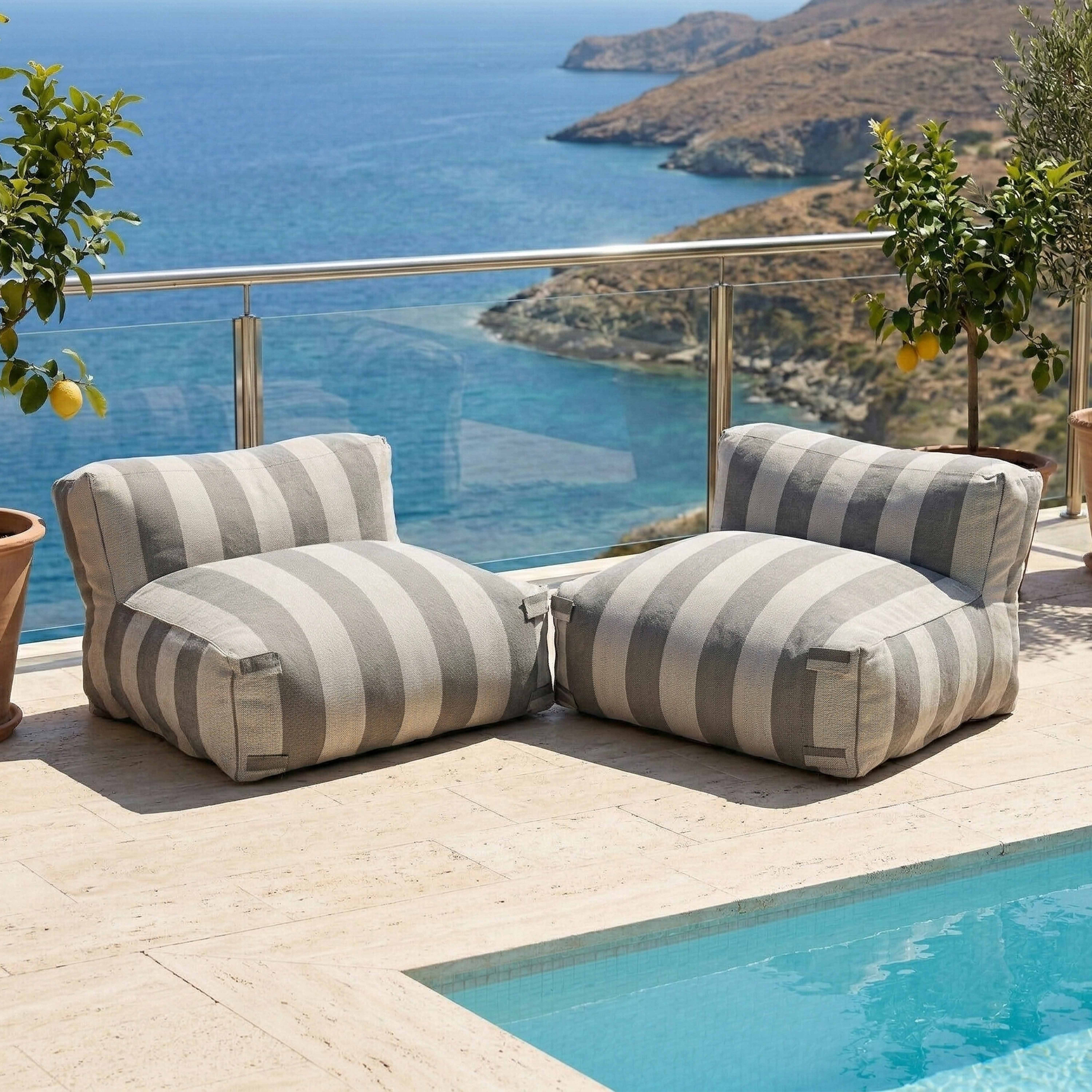 Zwei gestreifte Sessel am Pool mit Blick auf das Meer und die Berge.