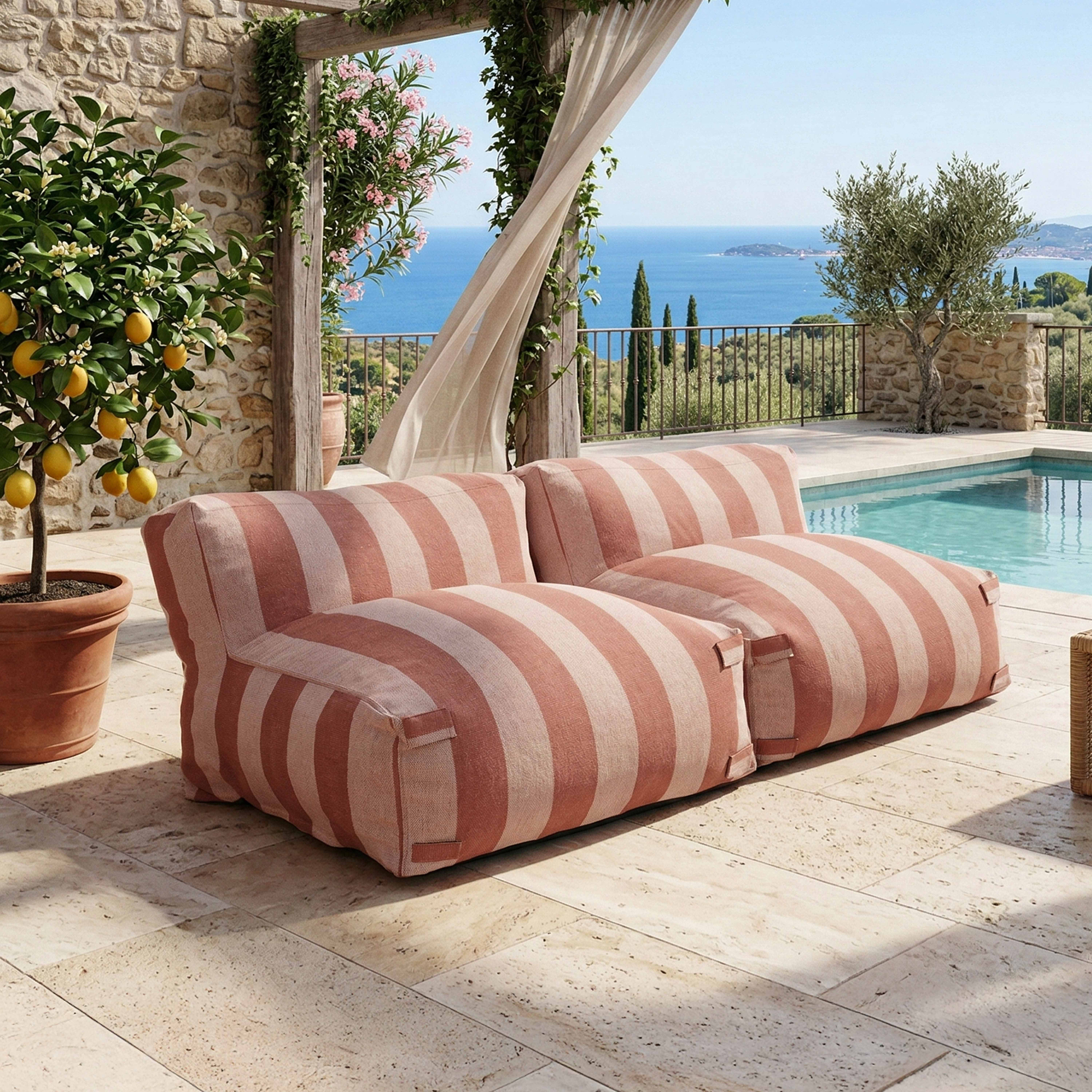 Gestrandete gestreifte Sofas am Pool mit Blick aufs Meer.