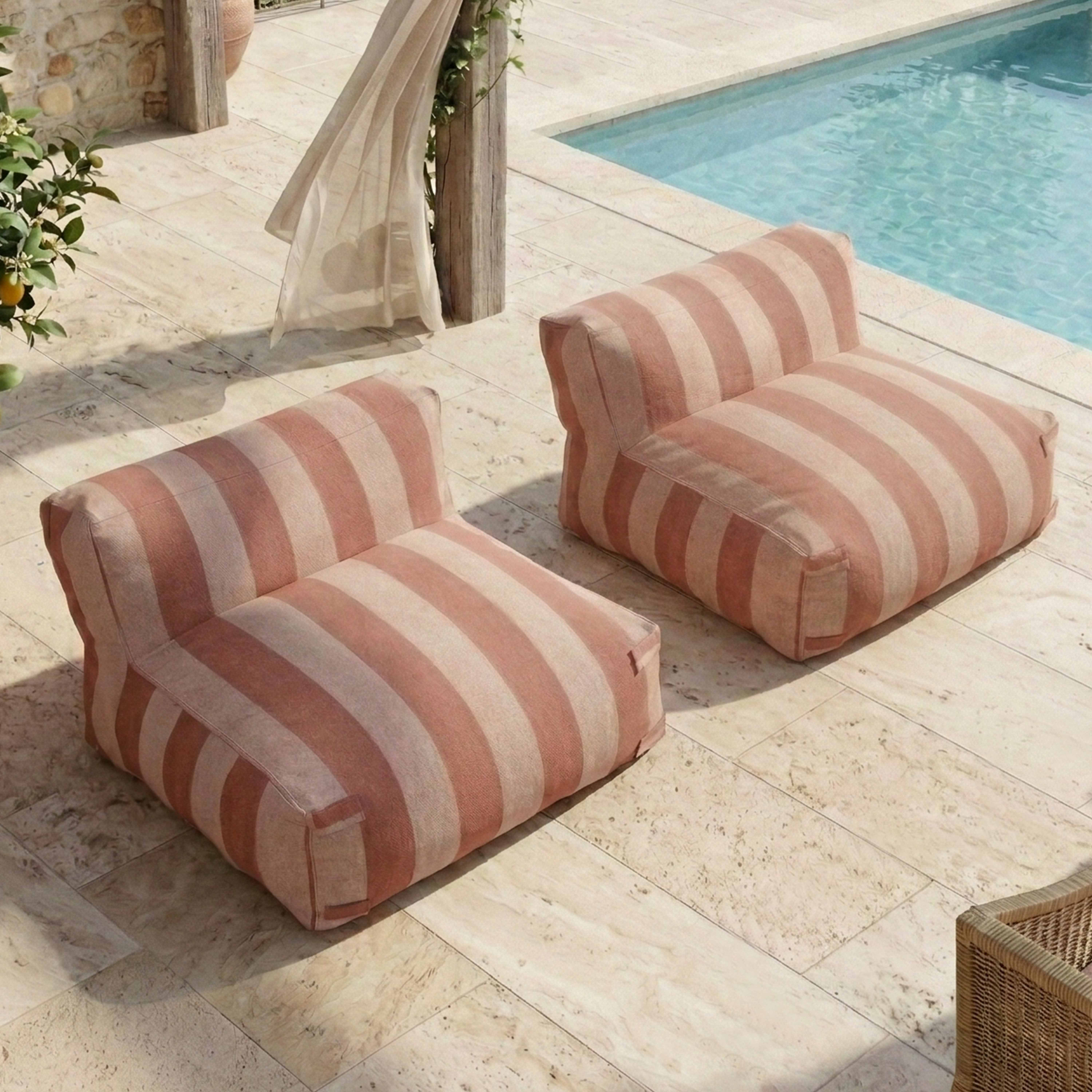 Zwei gestreifte Sessel stehen auf einer gefliesten Terrasse neben einem Pool.