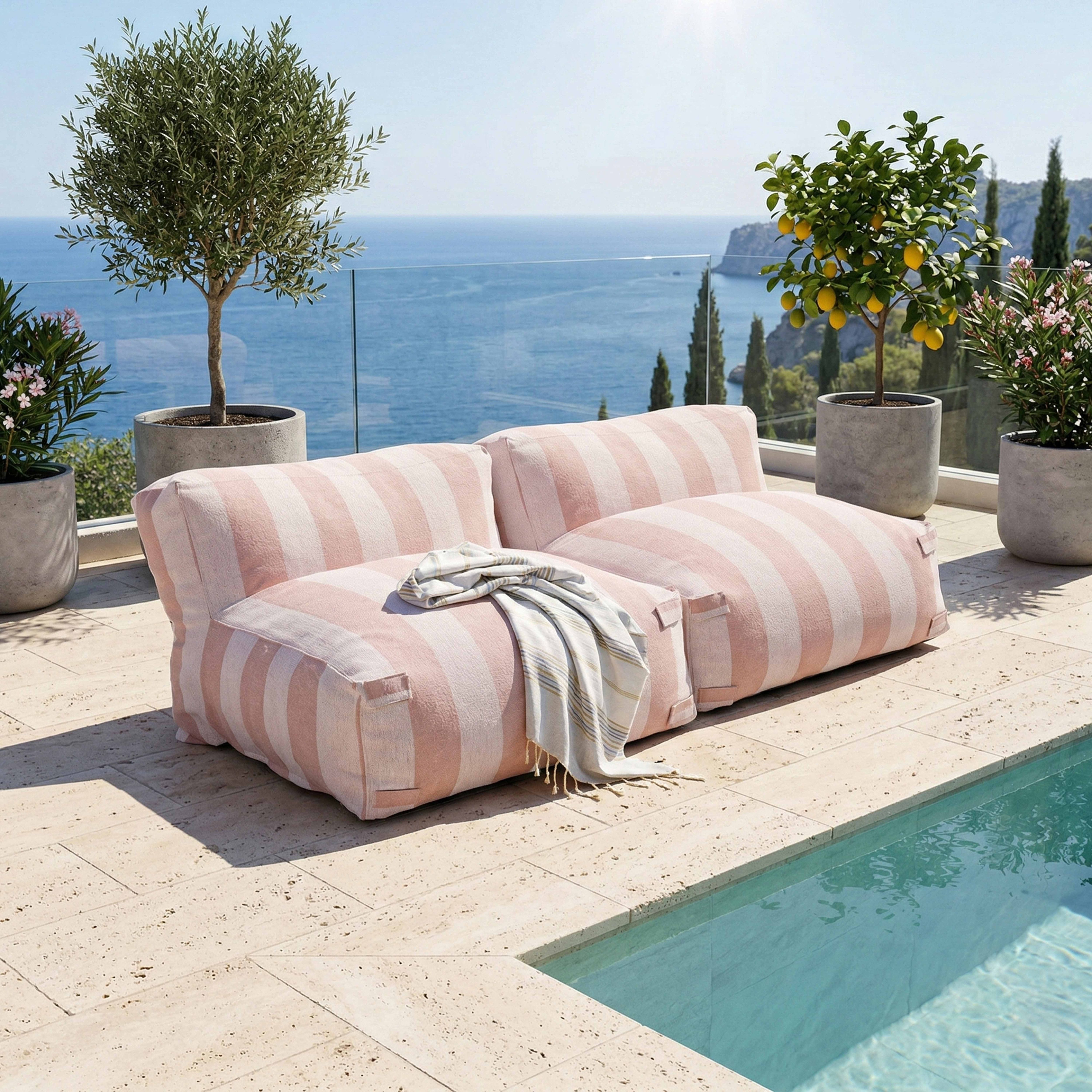 Ein gestreiftes rosa Outdoor-Sofa steht neben einem Pool mit Blick auf das Meer.