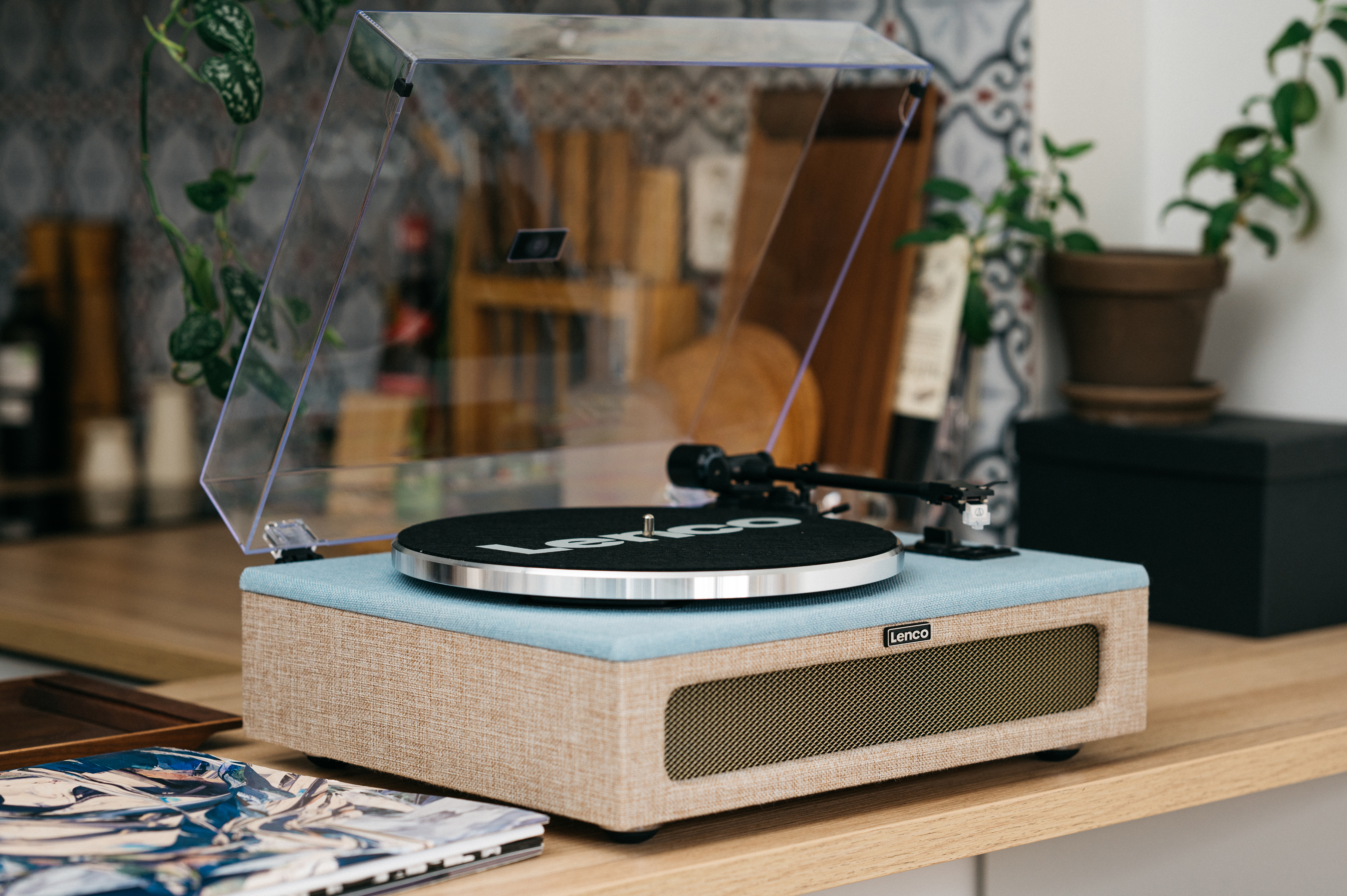 Een platenspeler met blauwe stof en houten behuizing staat op een tafel.