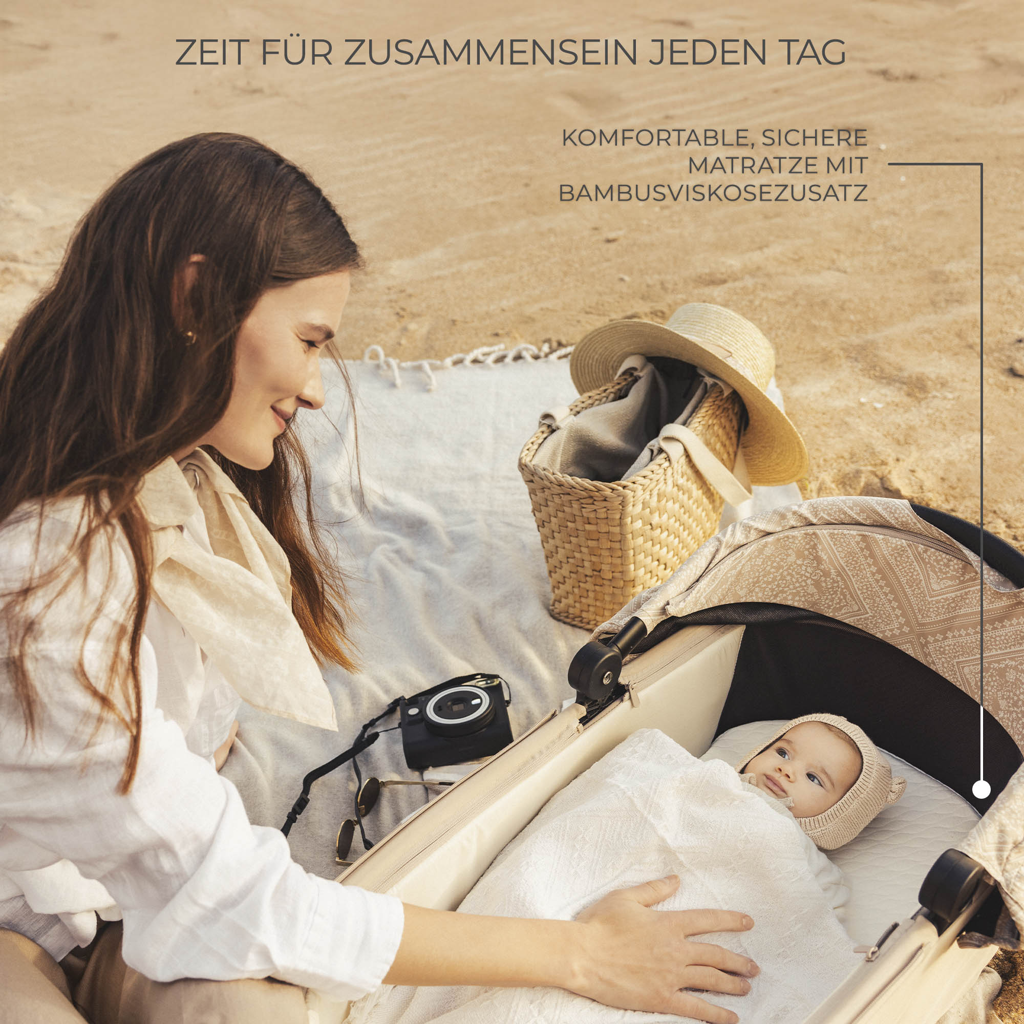 Mutter blickt auf Baby in Kinderwagen am Strand, mit Picknickkorb und Kamera.