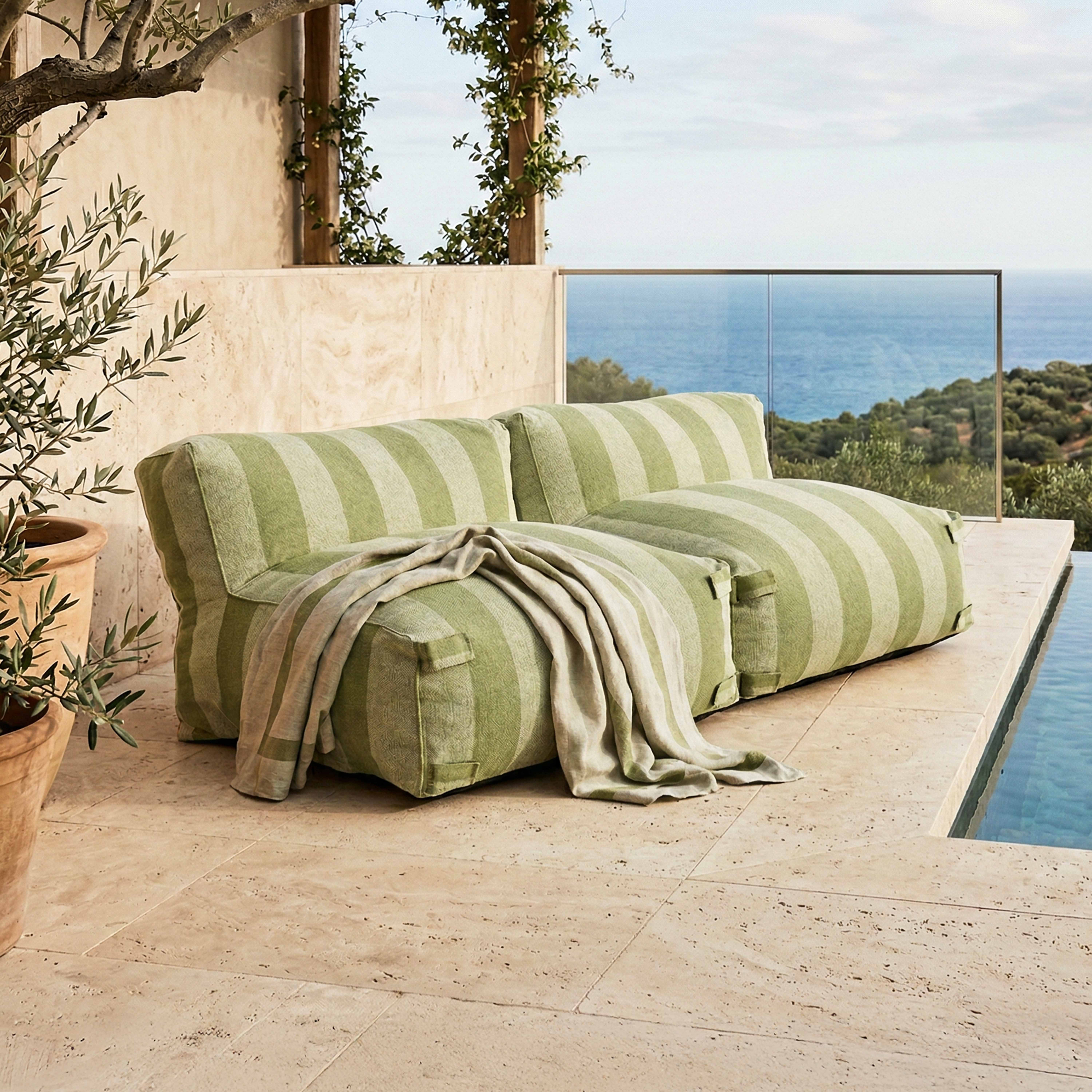 Grünes gestreiftes Sofa am Pool mit Meerblick und Olivenbaum.
