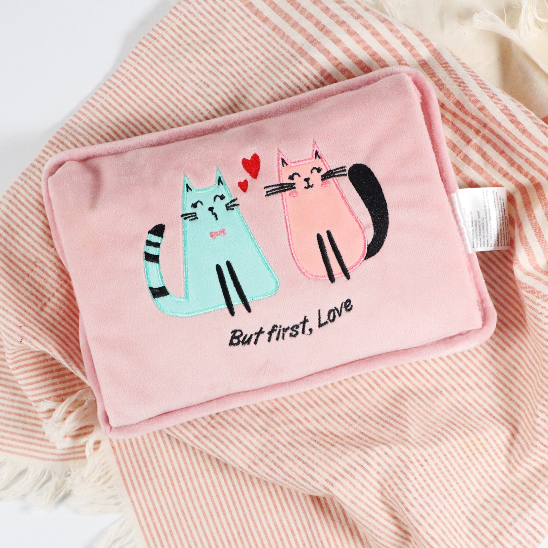 İki nakışlı kedi, biri mavi, biri pembe ve kalplerle süslenmiş pembe yastık.