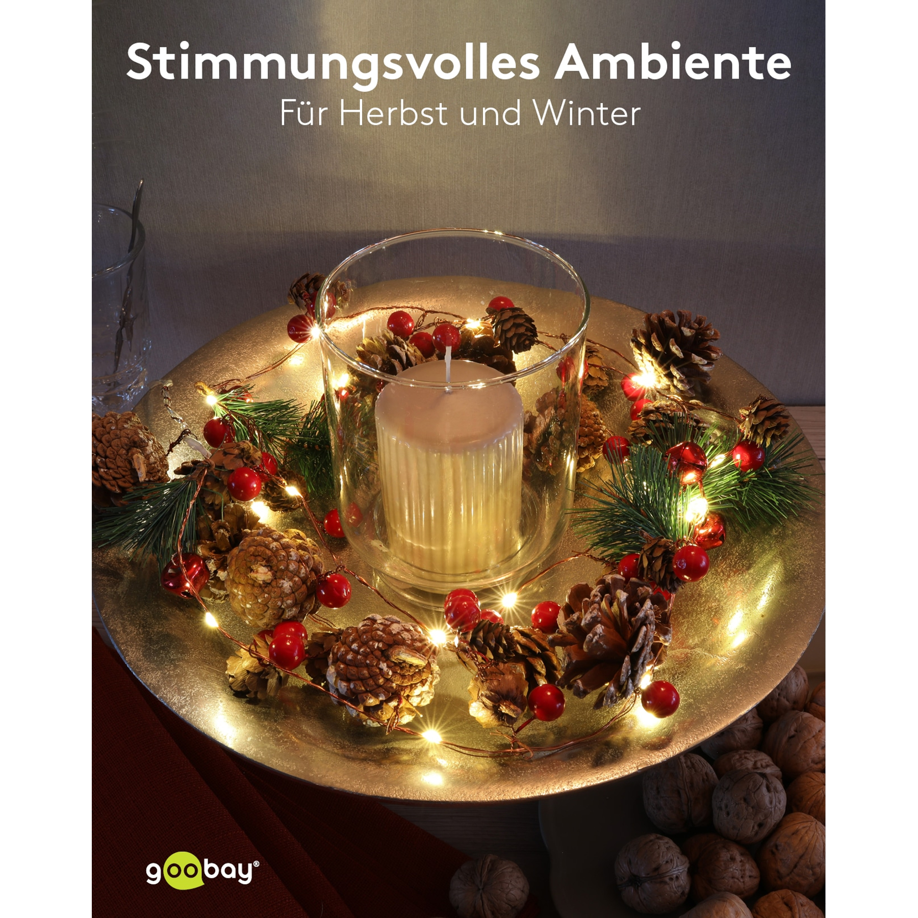 Kerze in Glas mit Tannenzweigen, Zapfen, Beeren und Lichterkette.
