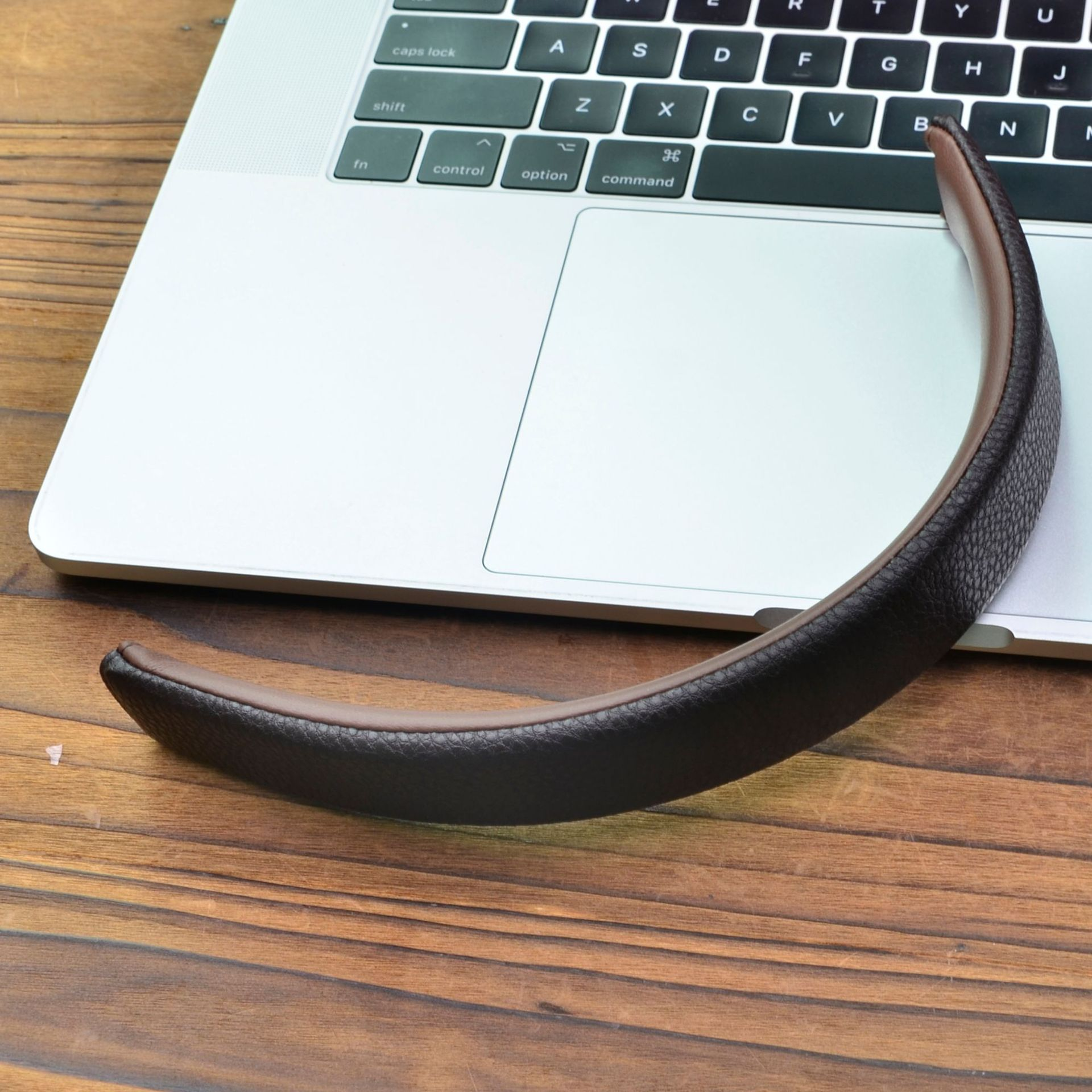 Una fascia in pelle marrone poggia sulla tastiera di un laptop e scrivania.