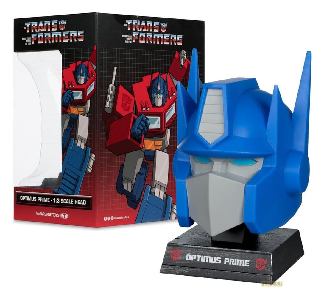 Replica della testa di Optimus Prime su un piedistallo accanto alla sua confezione.