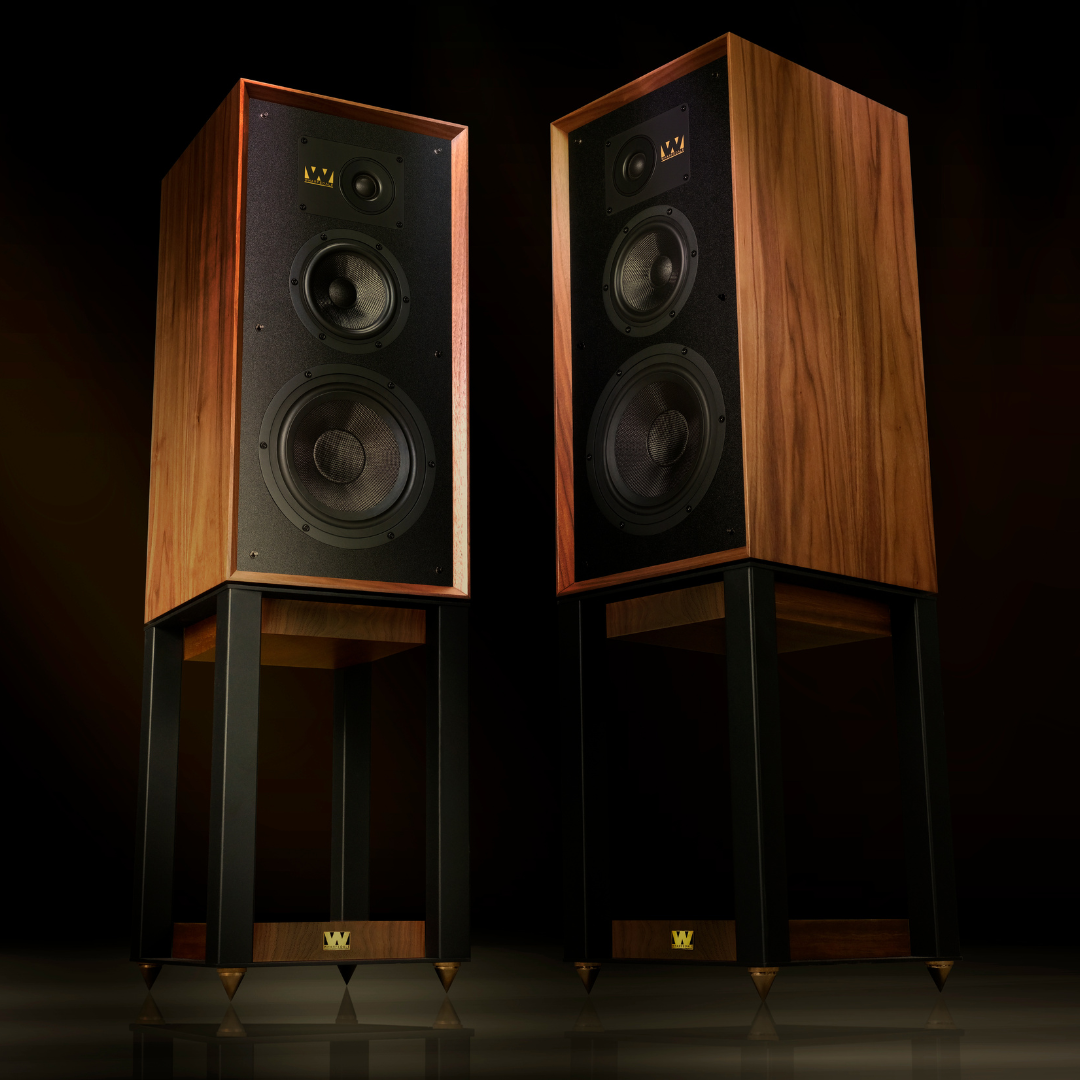 Twee houten luidsprekers met zwarte fronten op donkere standaards.
