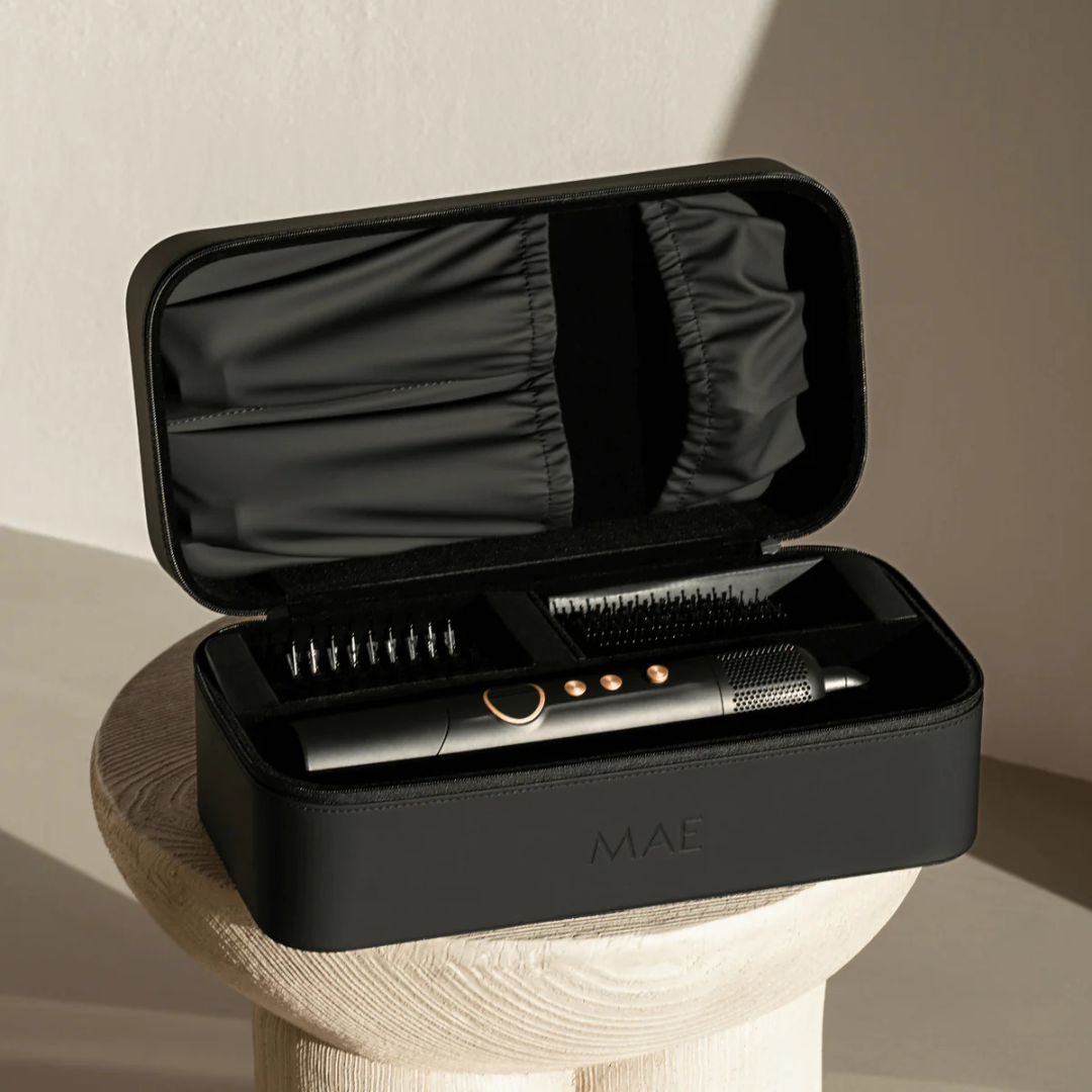 A black MAE hair styling set with attachments in an open travel case on a stool.