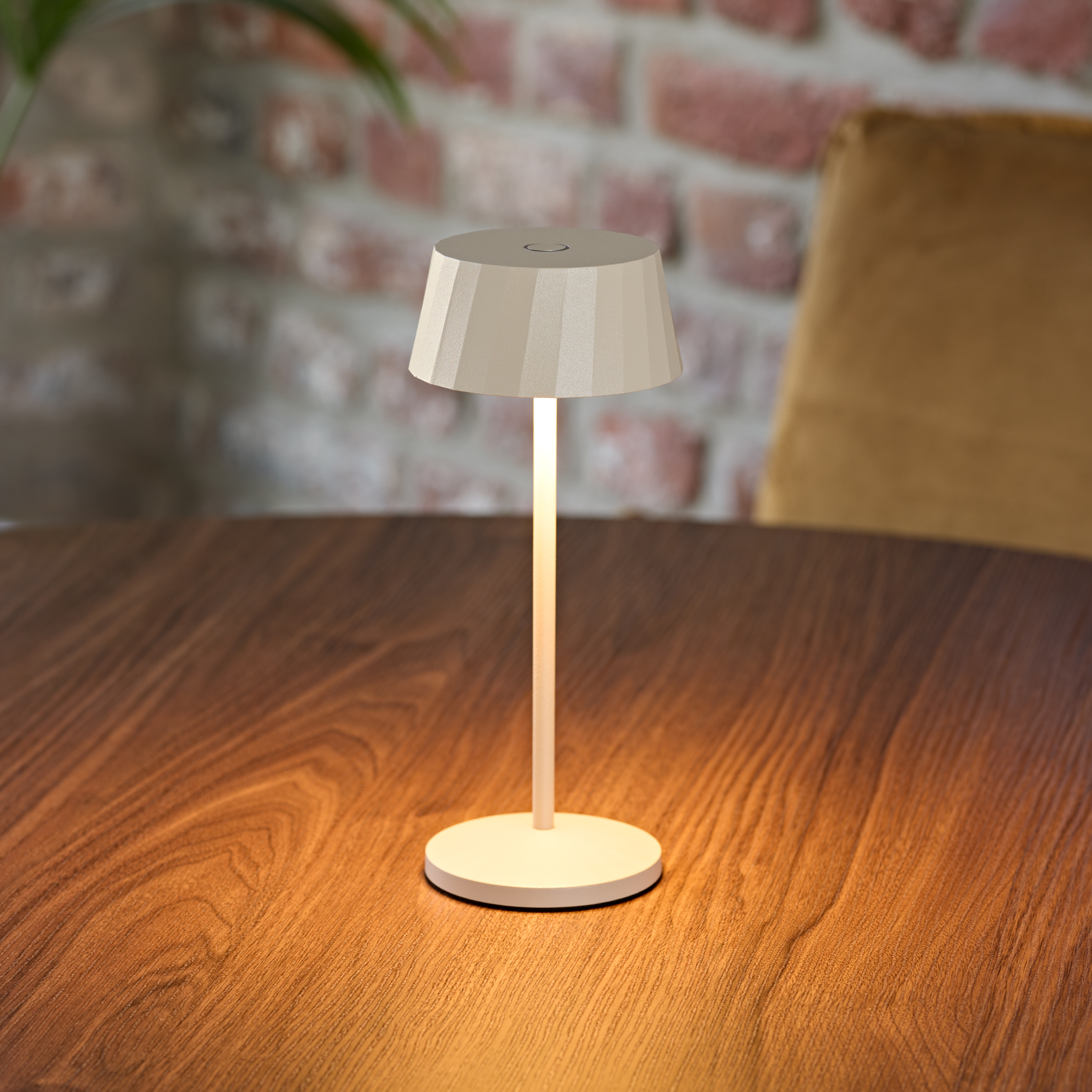 Eine schlichte Tischlampe mit einem hellen Schirm steht auf einem Holztisch.