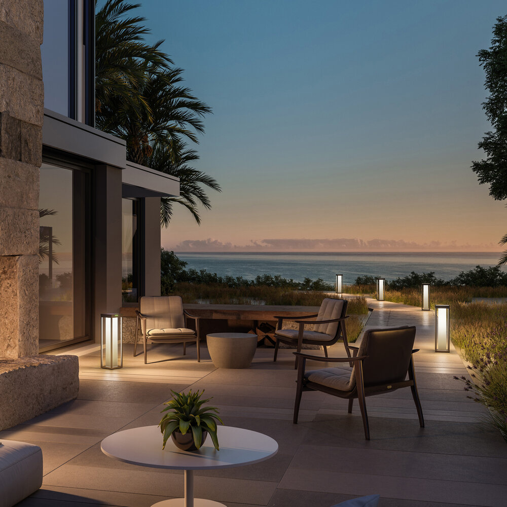 Eine Terrasse am Meer bei Dämmerung mit Stühlen, Tisch und Beleuchtung.
