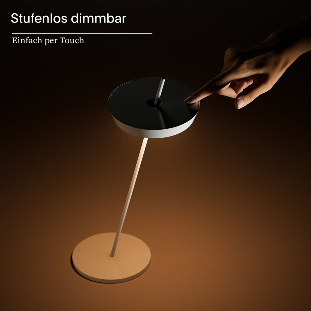 Eine Hand berührt eine moderne weiße Lampe mit schwarzer Oberseite.
