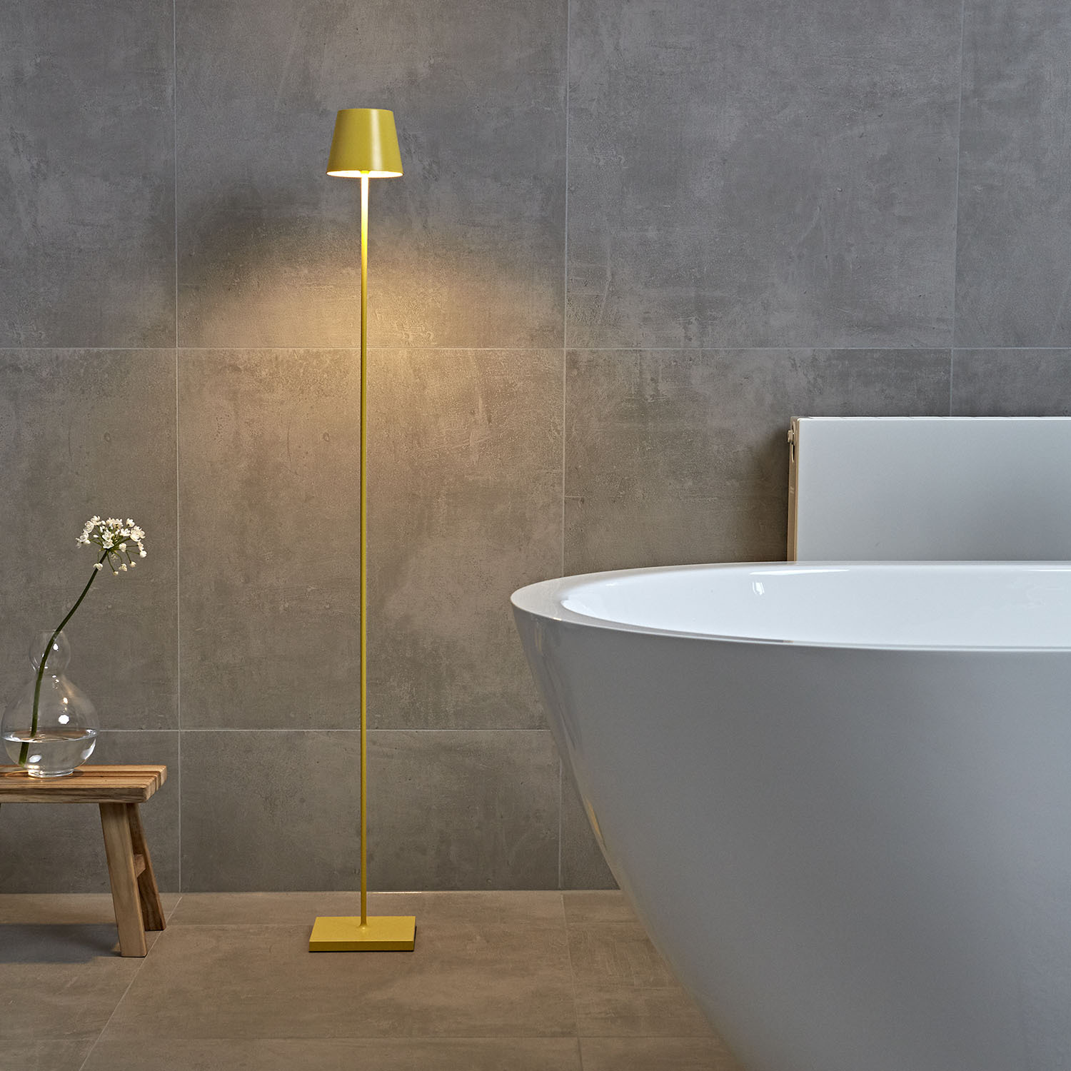 Ein gelber Stehlampen beleuchtet ein Badezimmer mit einer Badewanne.