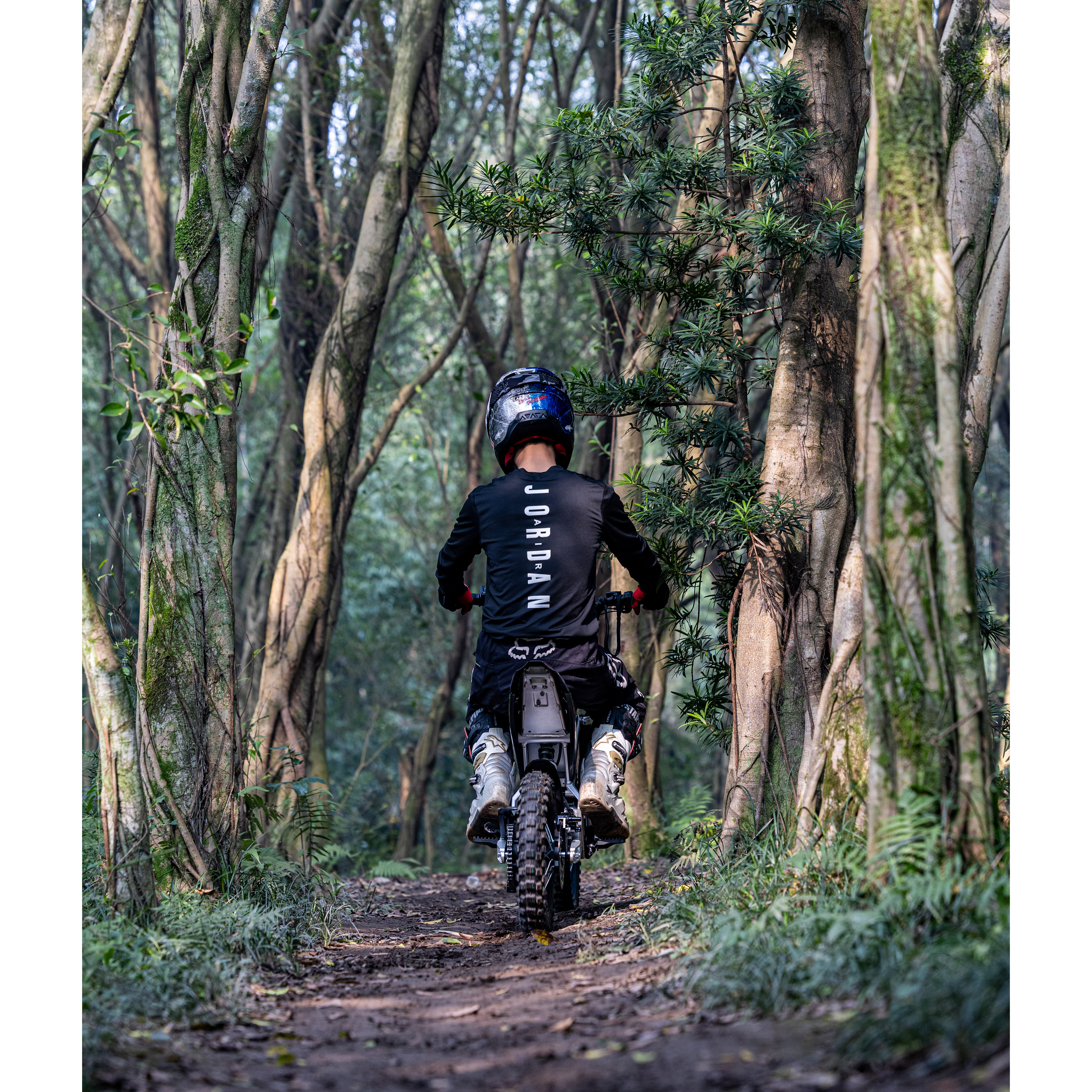 Ein Fahrer auf einem Motorrad fährt auf einem Waldweg.