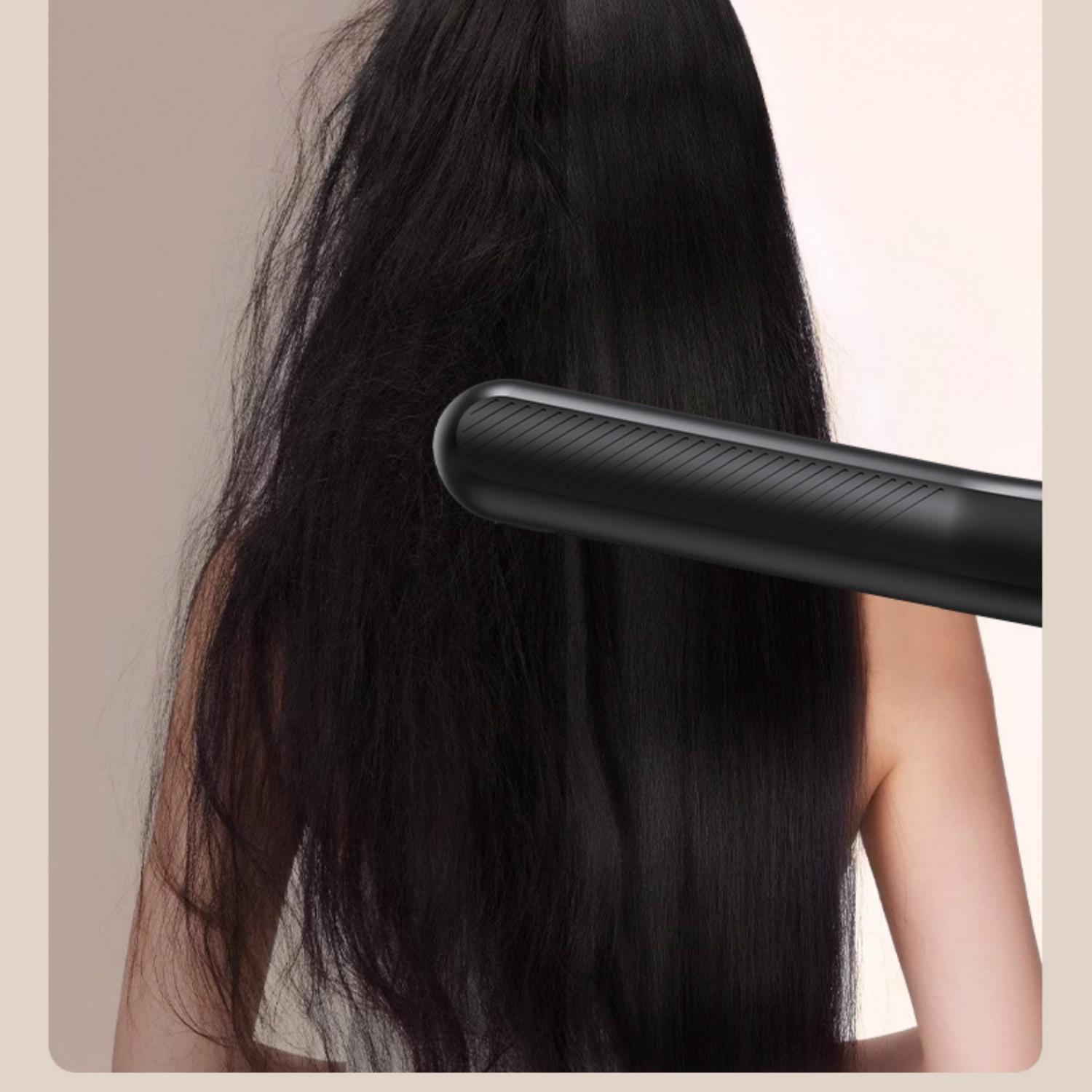 Eine Person mit langen, dunklen Haaren, die von einem schwarzen Glätteisen geglättet werden.