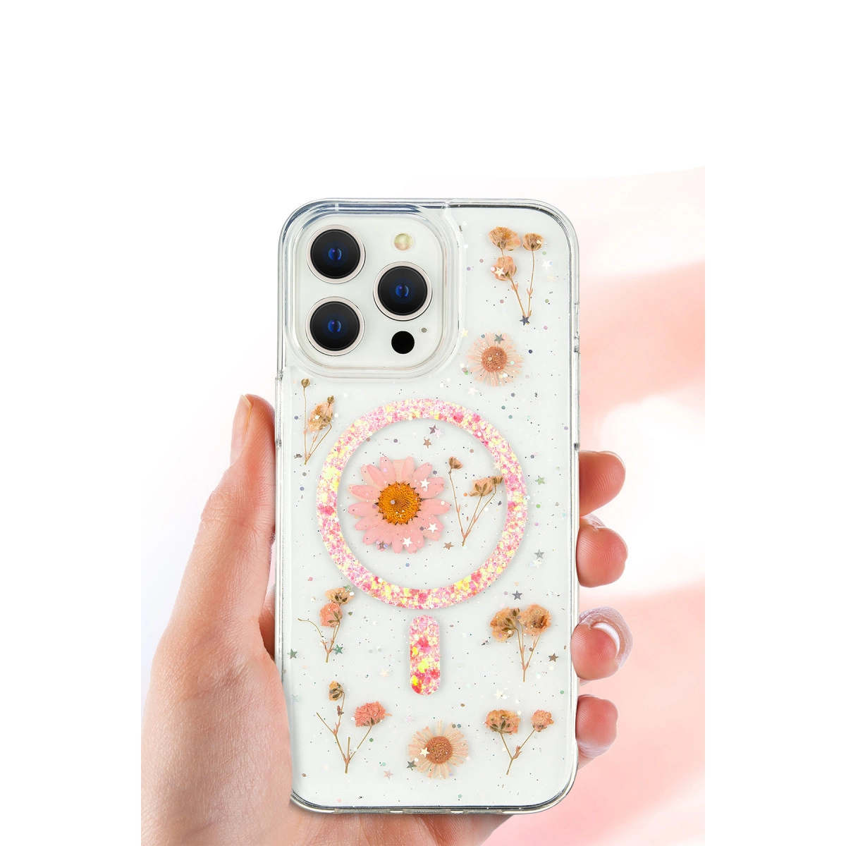 Kuru çiçekler ve simlerle süslü şeffaf telefon kılıfını tutan el.