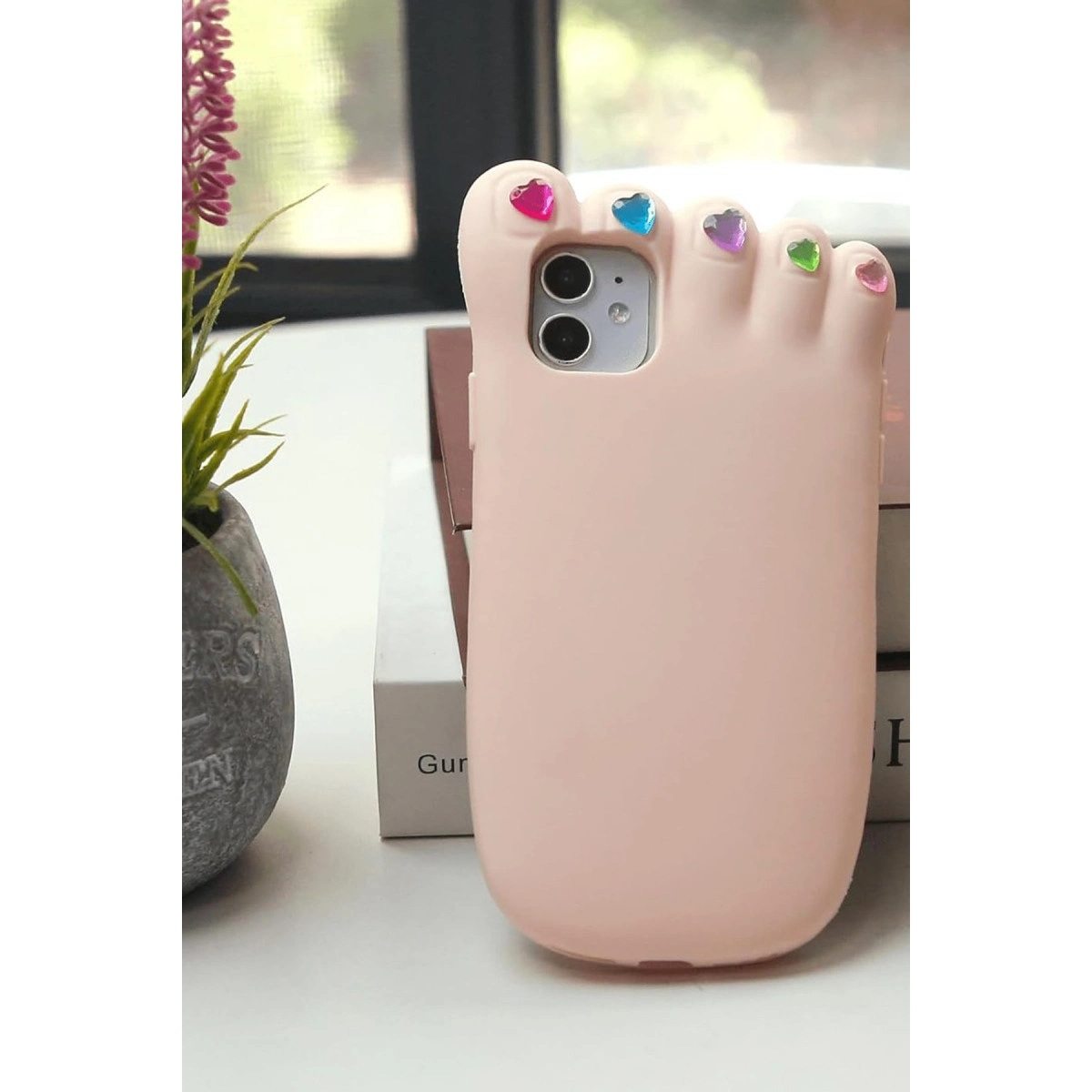 Renkli kalp tırnak süslemeli, pembe ayak şekilli telefon kılıfı.