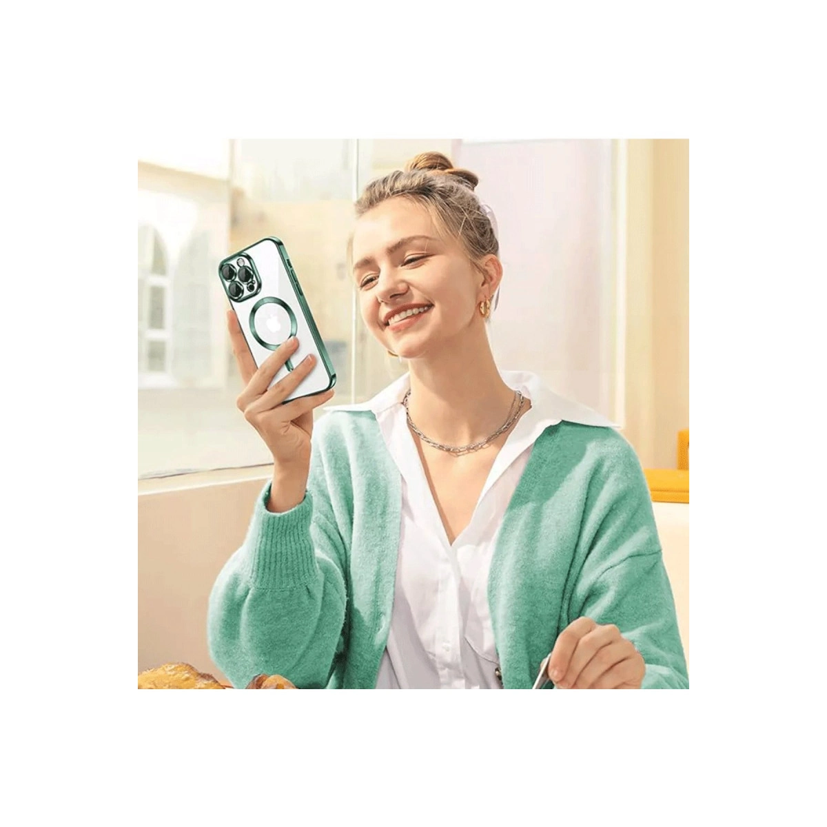 Kadın yeşil kılıflı ve halka tutuculu bir telefon tutuyor.