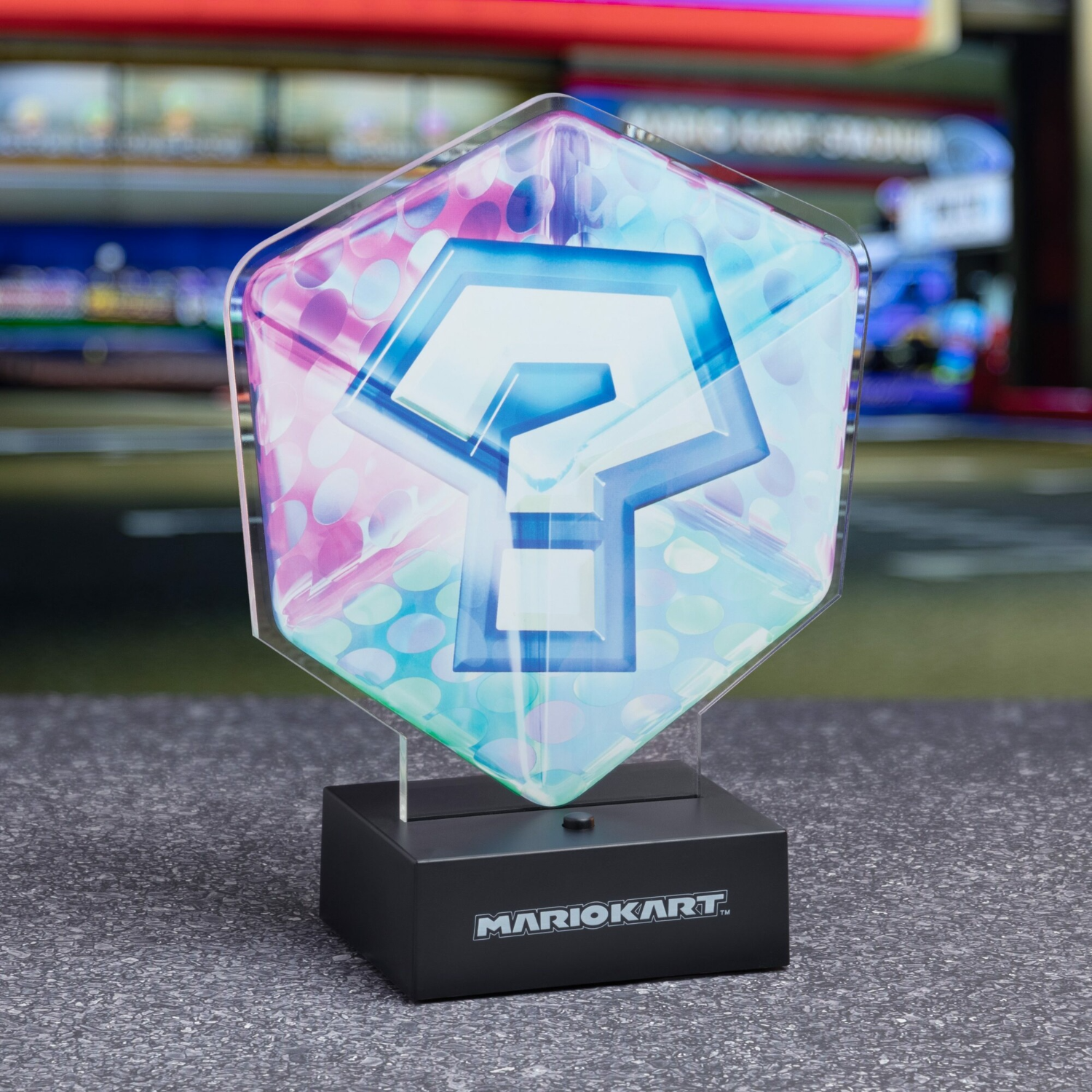 Ein Fragezeichen-Item aus Mario Kart auf einem Sockel mit dem Logo.