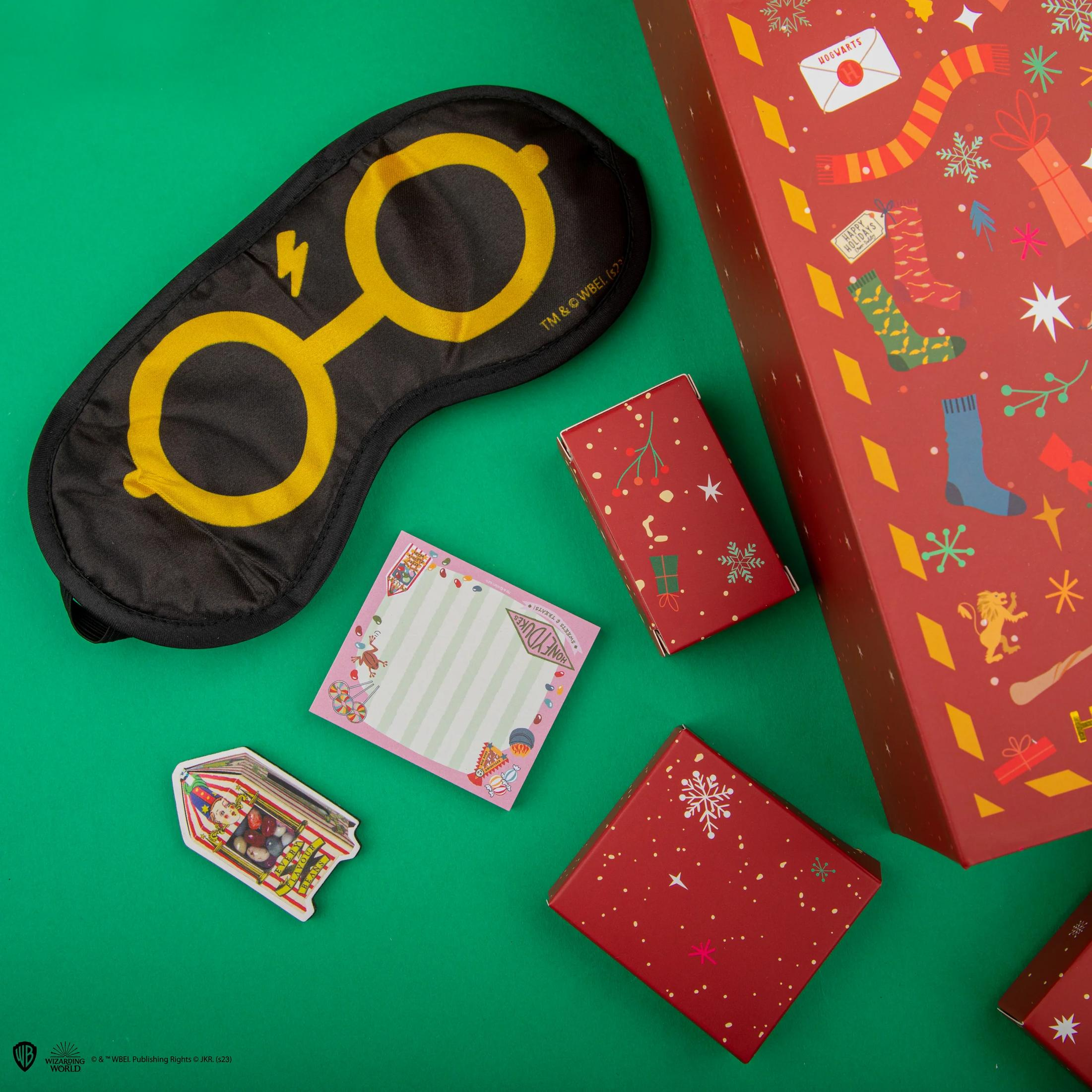 Harry Potter Schlafmaske, Notizblock, Bohnen und Weihnachtsboxen auf grünem Untergrund.