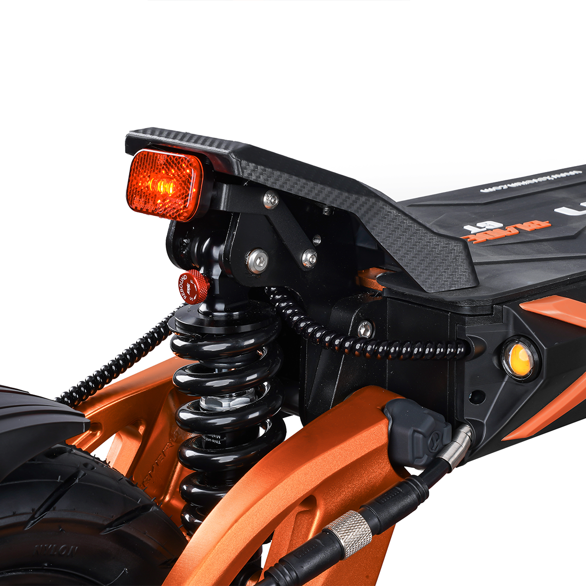 Zbliżenie tylnego zawieszenia i tylnego światła pomarańczowo-czarnej hulajnogi elektrycznej.