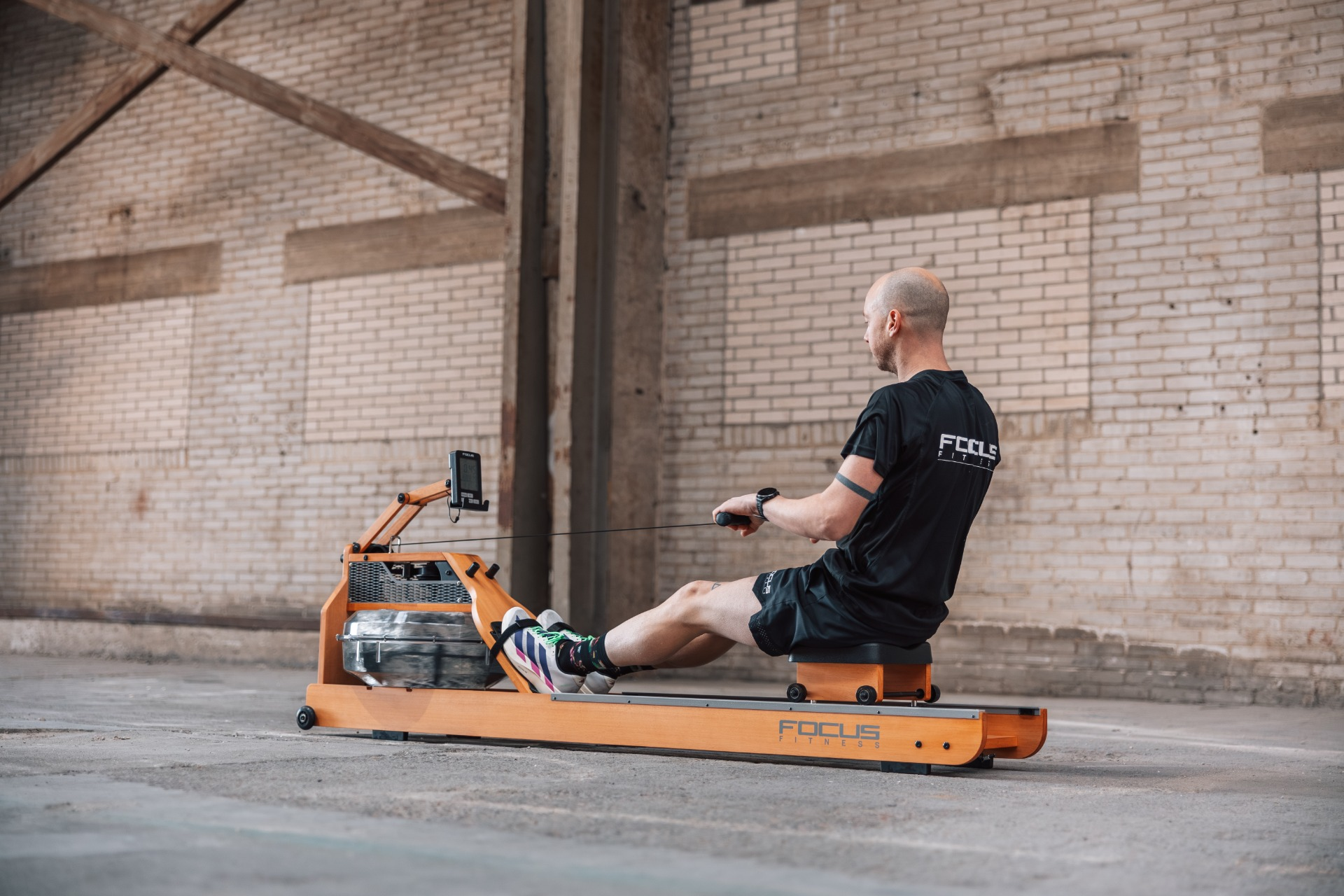Man on a rowing machine in an industrial building.