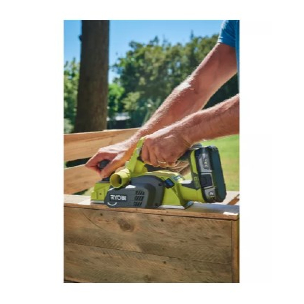 Uomo pialla legno con pialla a batteria verde all'aperto in una giornata di sole.