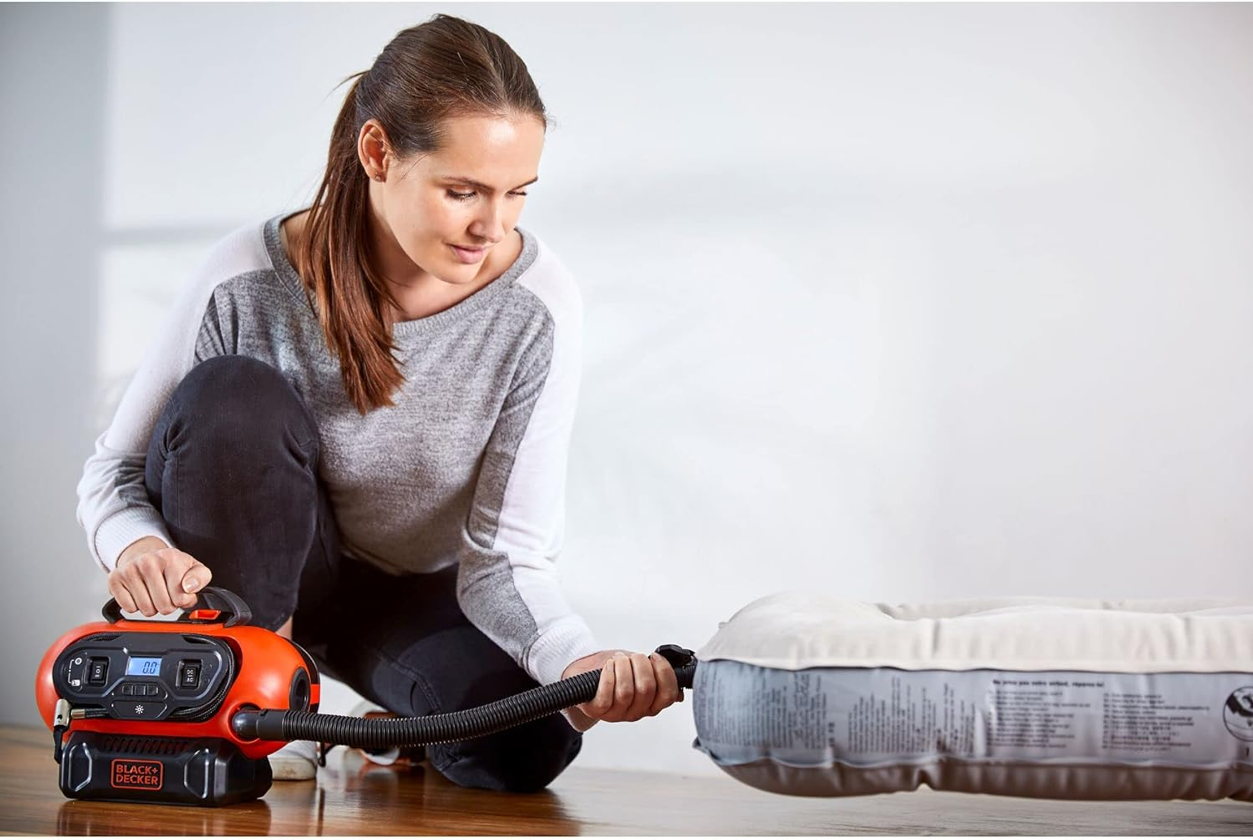 Kobieta pompuje materac dmuchany pomarańczowym urządzeniem.