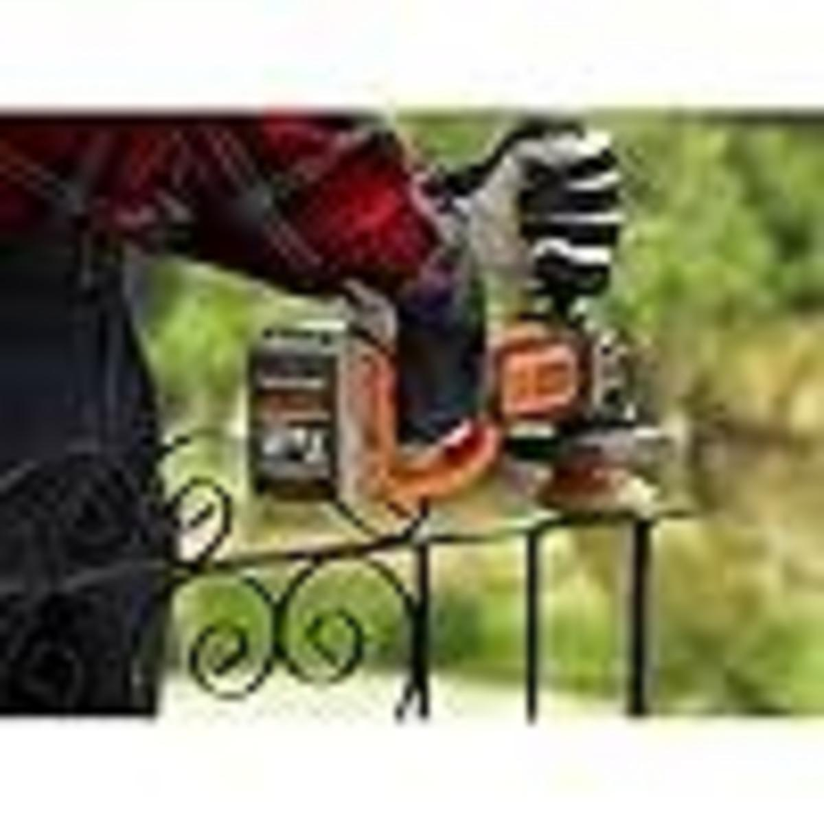 Osoba w koszuli w kratę trzyma piłę łańcuchową nad balustradą.