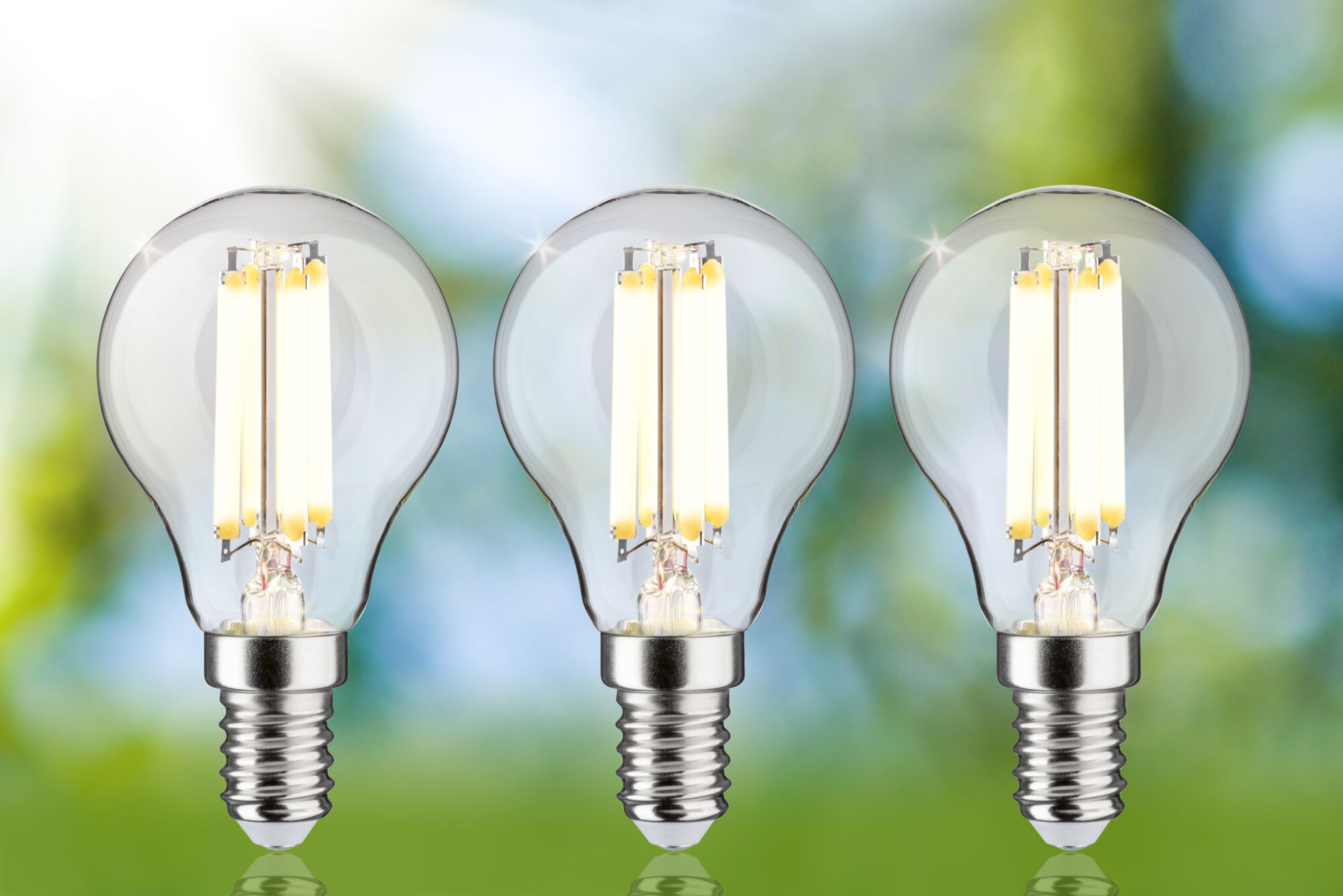 Trzy przezroczyste żarówki LED ze srebrnymi podstawami, oświetlone.