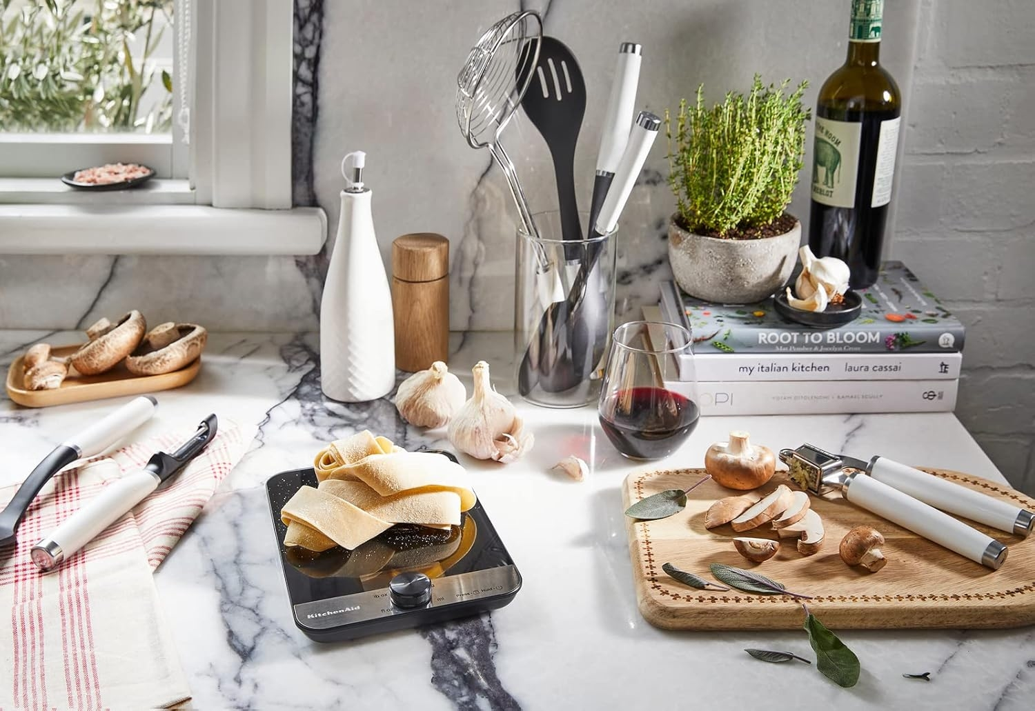 Frische Pasta auf Küchenwaage, Pilze, Knoblauch, Kräuter, Wein, Kochbücher.