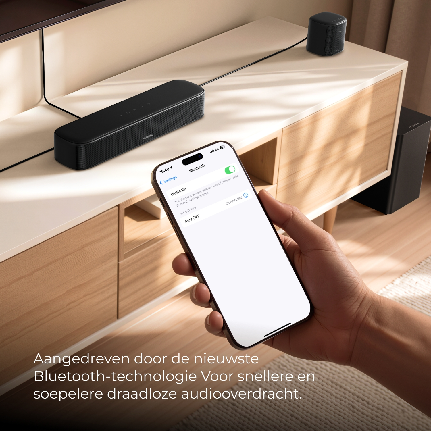 Main tenant un smartphone avec paramètres Bluetooth. Barre de son et haut-parleur en arrière-plan.