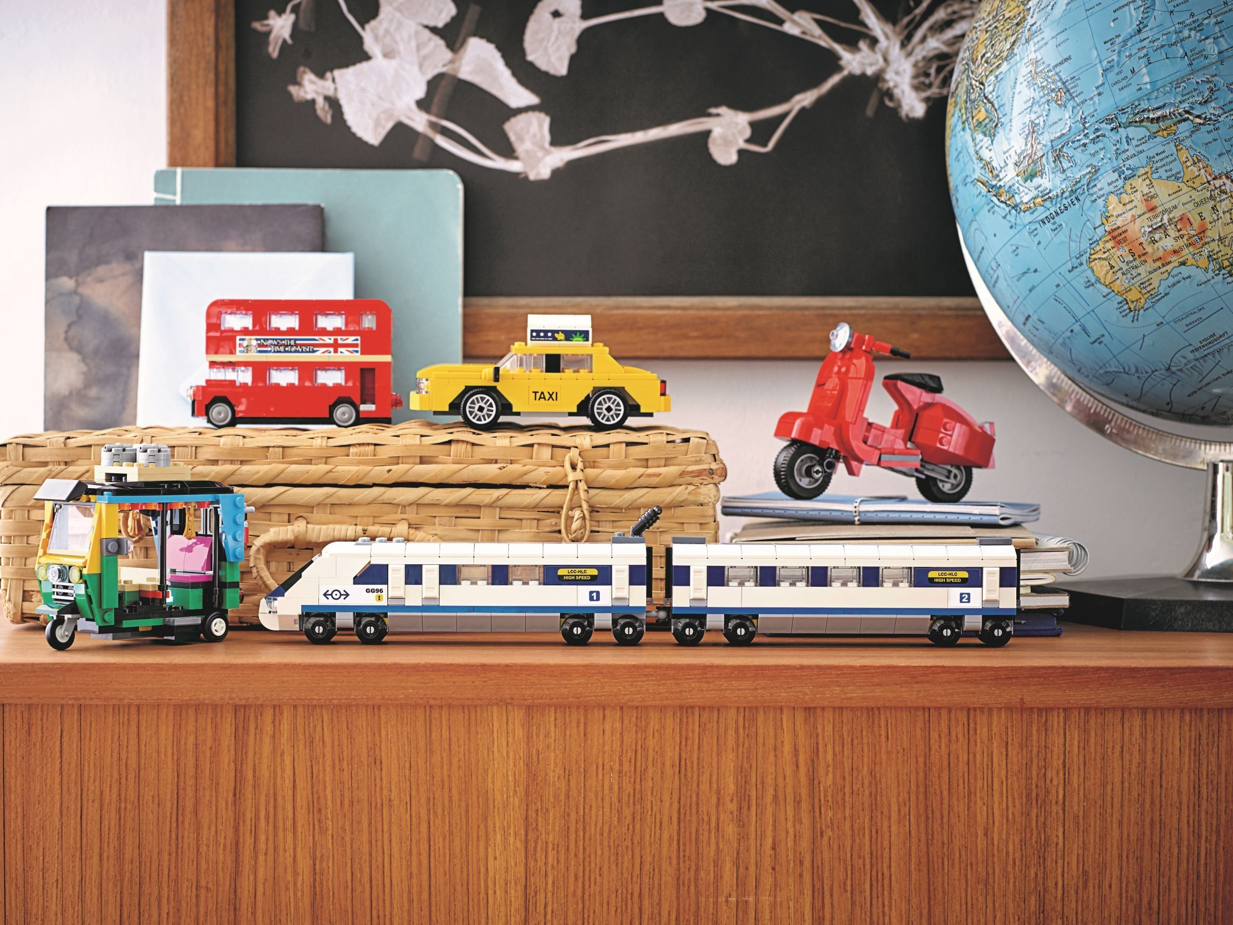 Modelli Lego: tuk-tuk, bus rosso a due piani, taxi, scooter rosso, treno e mappamondo.