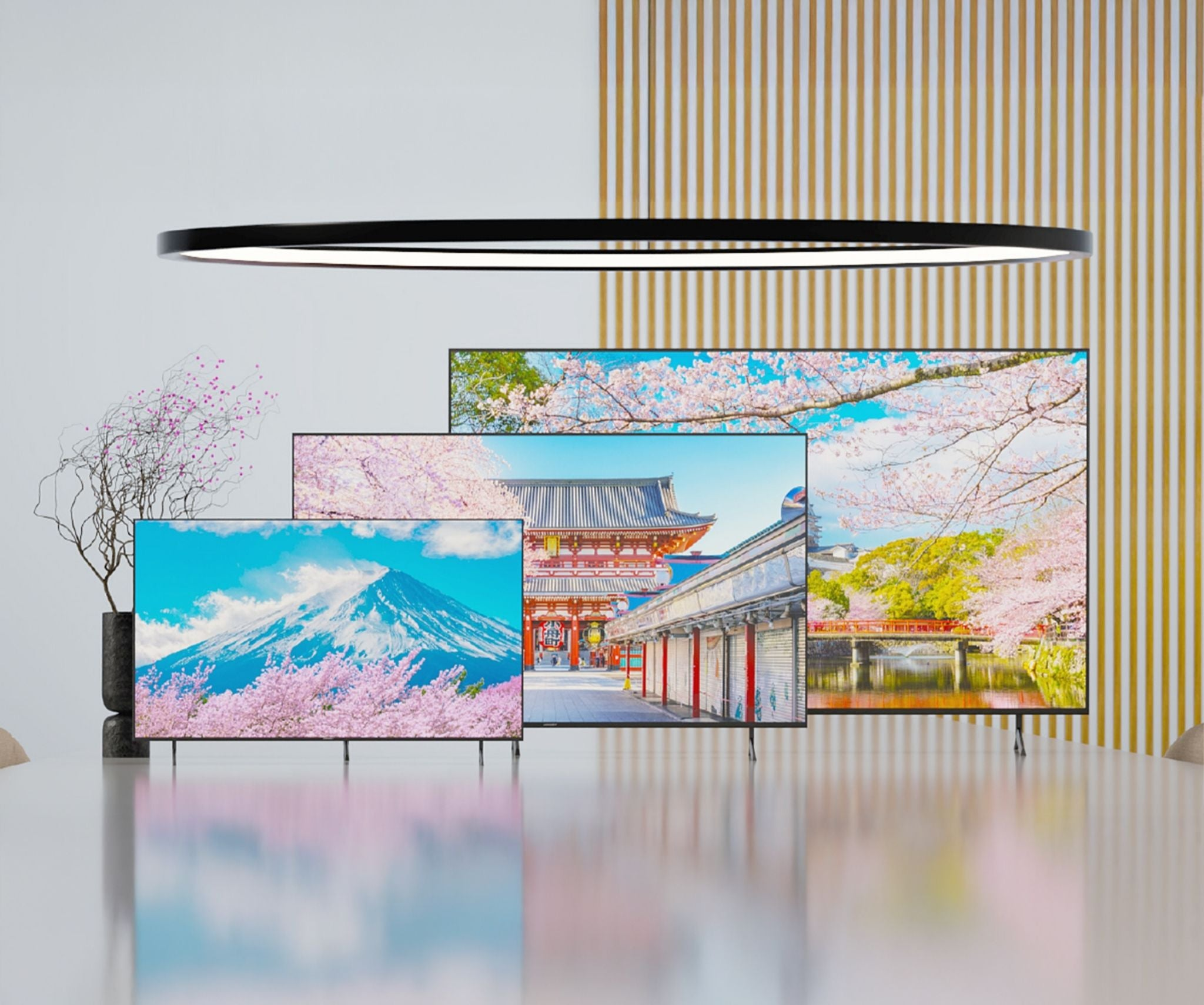 Tres televisores muestran escenas japonesas con flores de cerezo y montañas.
