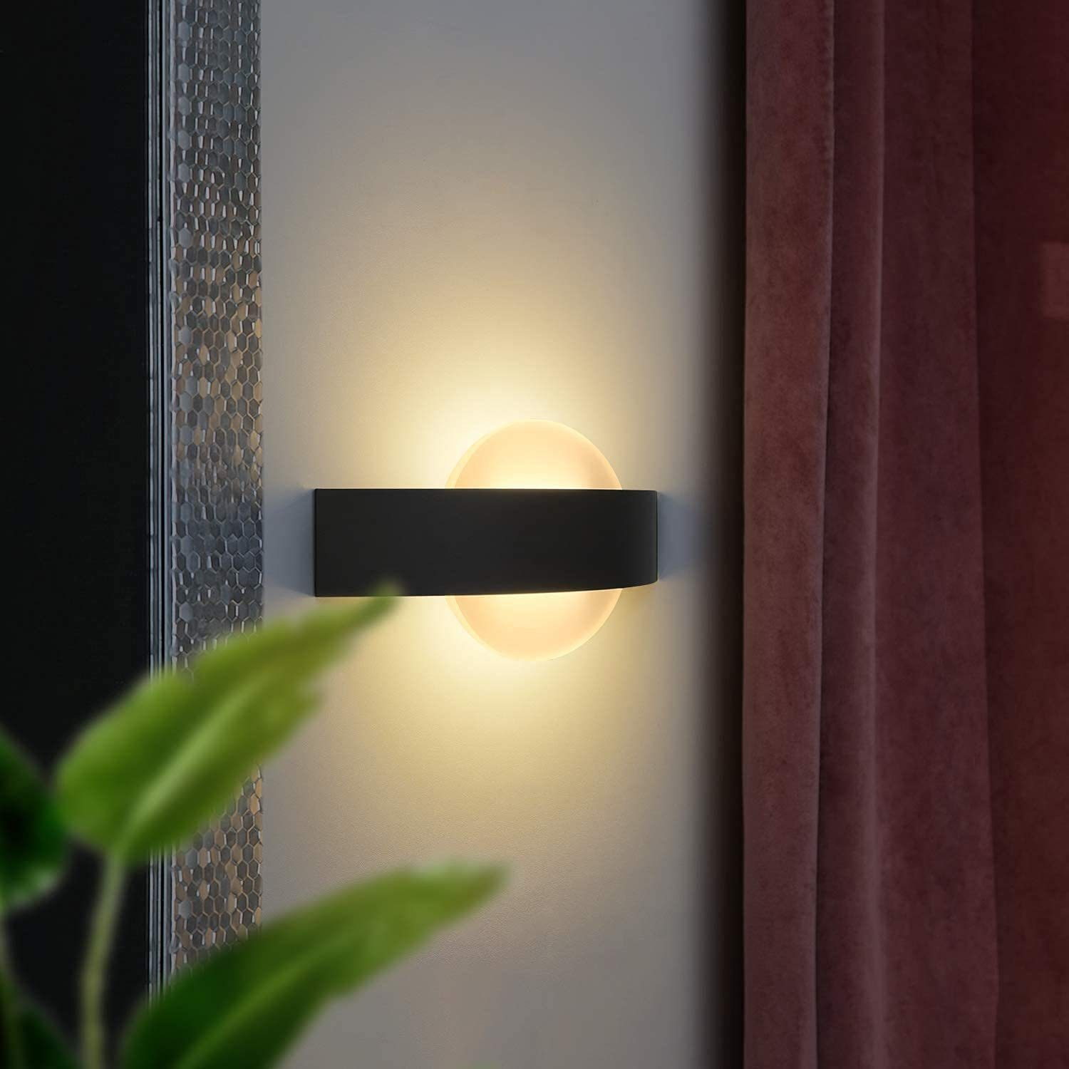 Una lampada da parete moderna con corpo nero e diffusore rotondo illuminato.