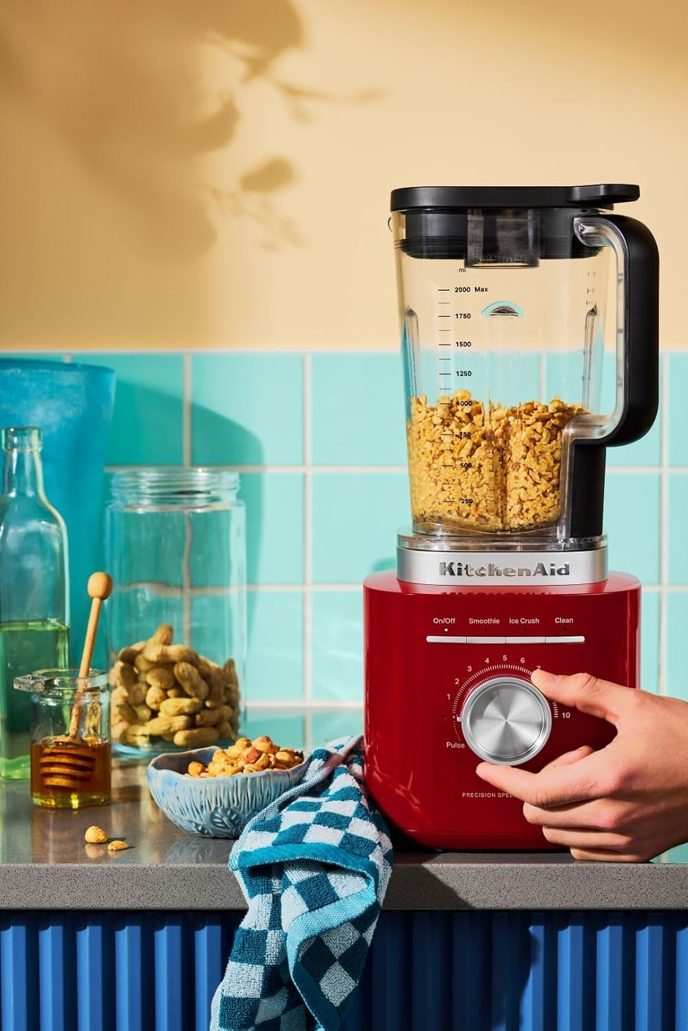 Kırmızı KitchenAid blender, ceviz, bal ve ekose havlu ile.