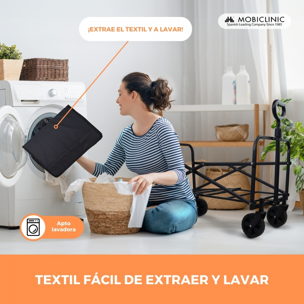 Una mujer saca una tela negra de una lavadora a una cesta de ropa.