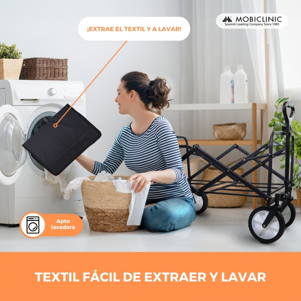 Mujer carga tela negra en lavadora, cesta cerca.