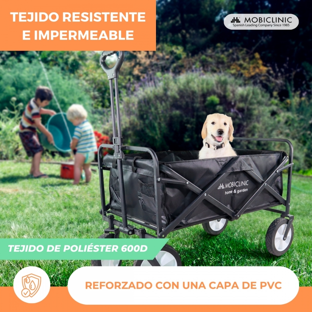 Un perro dorado sentado en un carro negro en un jardín. Niños juegan al fondo.