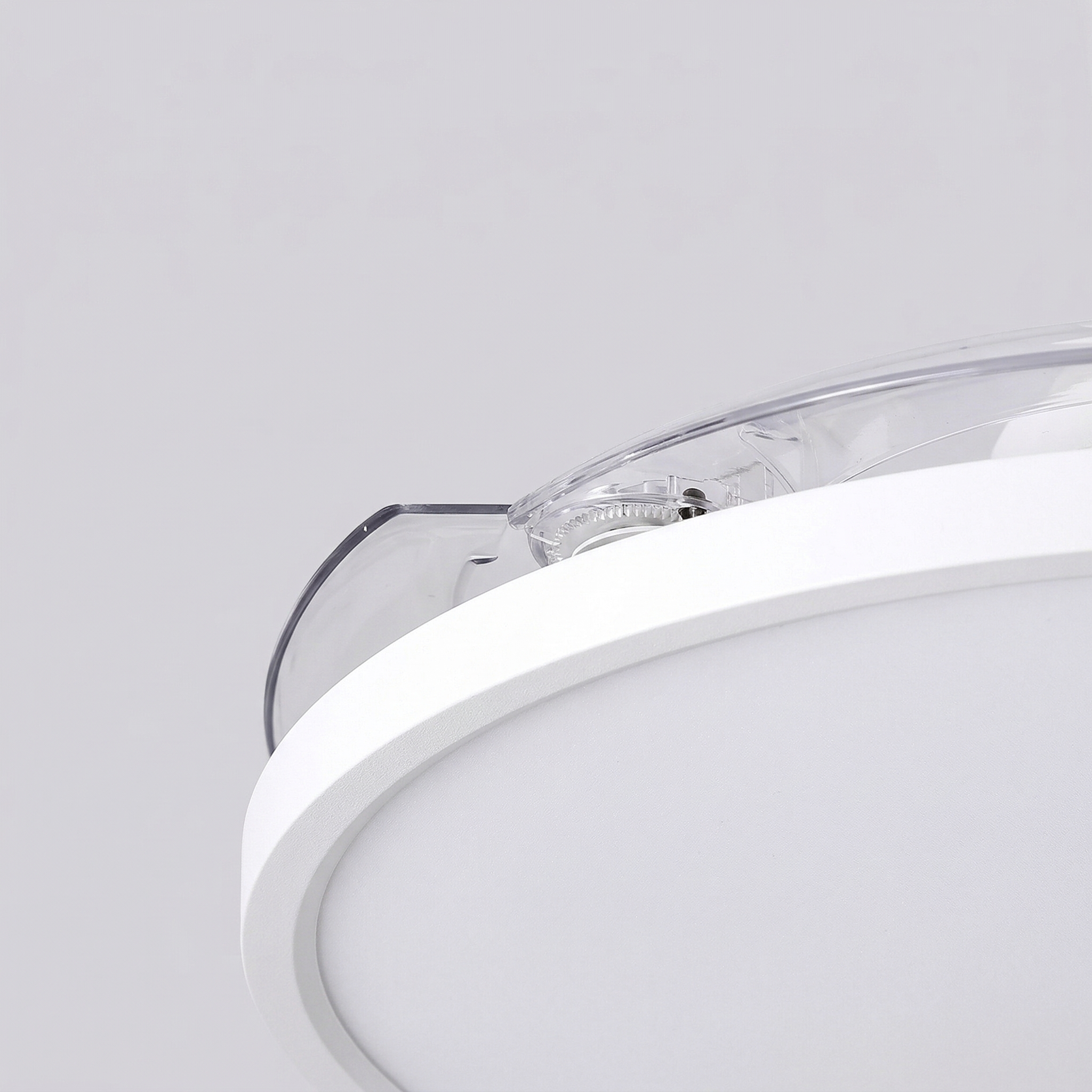 Primer plano de una lámpara de techo blanca con carcasa transparente y engranaje.
