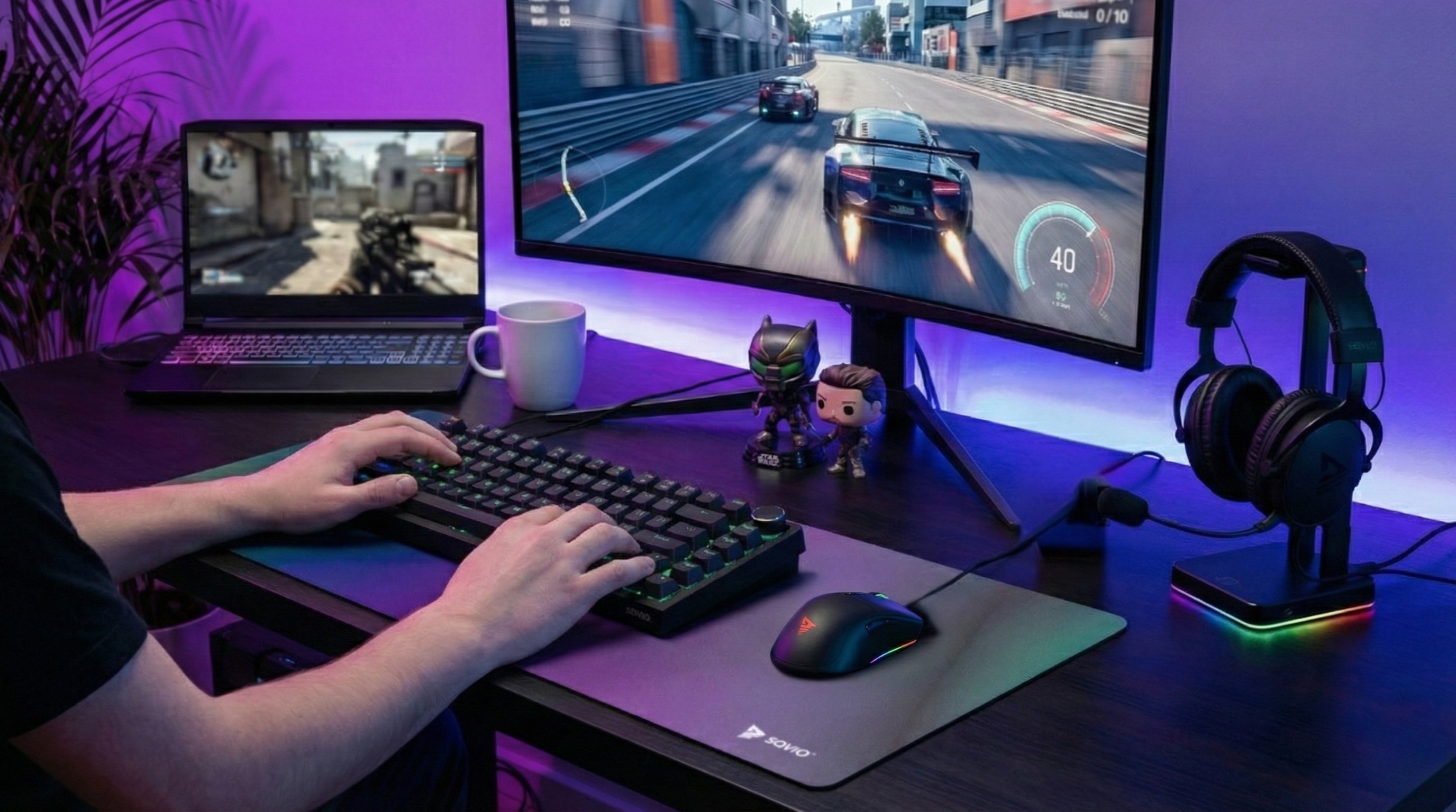 Osoba gra w wyścigi samochodowe na dużym monitorze, obok laptopa z grą strzelanką.